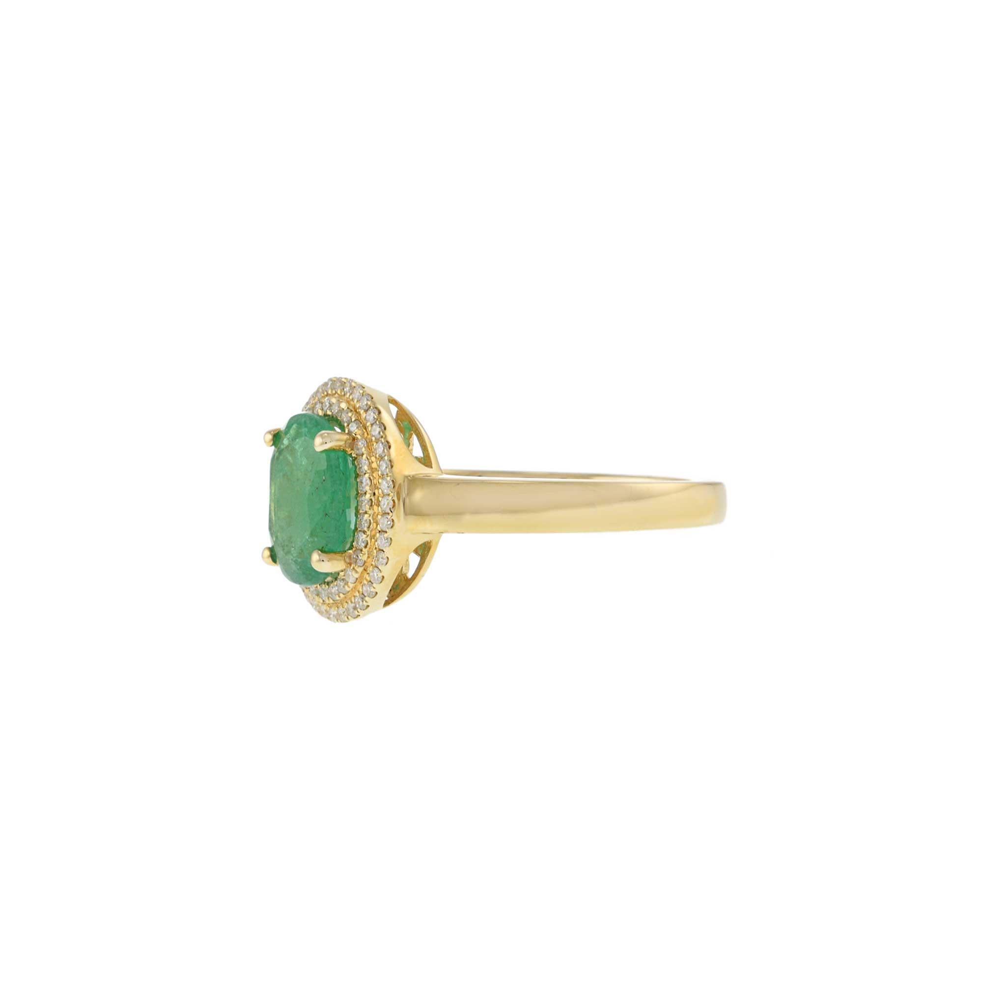 This exquisite ring features a 1.65 carat oval emerald, beautifully set in 14KT yellow gold. The vibrant emerald is surrounded by a double halo of round cut diamonds, totaling 0.19 carats. The combination of the rich green emerald and sparkling