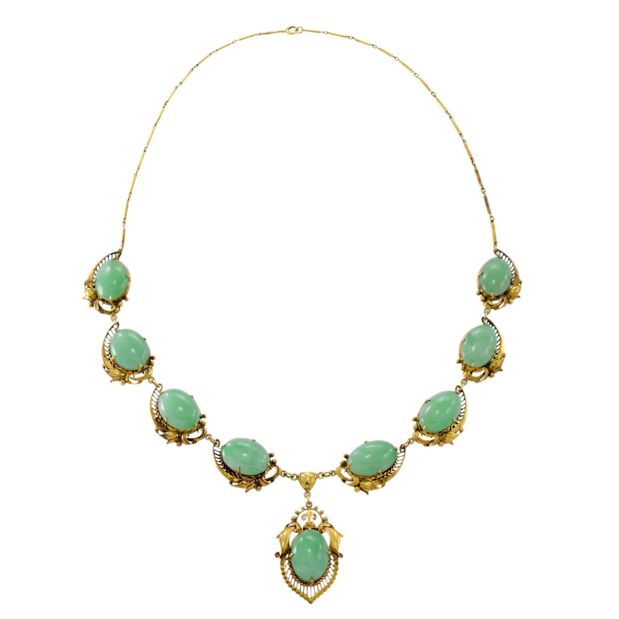 Cet élégant collier d'époque rétro est orné de neuf véritables pierres de jade vert cabochon, serties dans des motifs filigranés complexes. La combinaison de l'exquise fabrication en or jaune 14 carats et du travail filigrané détaillé rehausse la