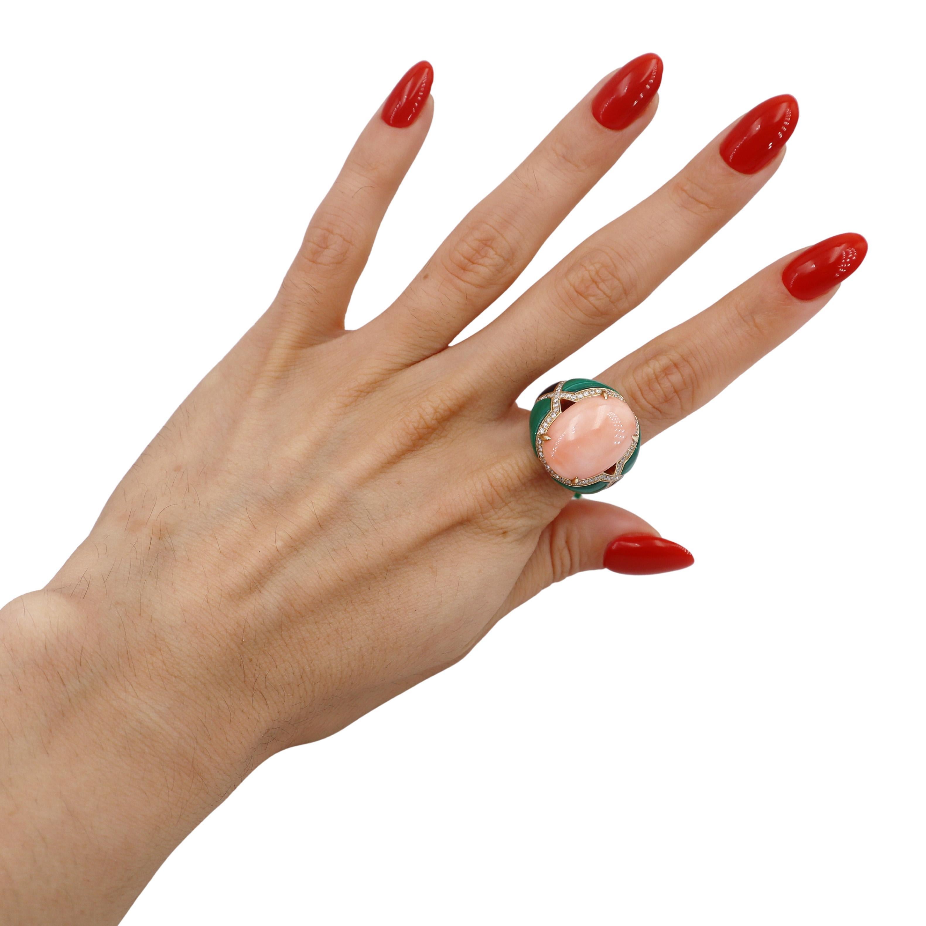 Introducing an exquisite 14kt yellow gold ring featuring a stunning cabochon coral of approximately 10.0 carats at its center. This elegant piece is enhanced by four polished malachite accents and two beautiful mother of pearl inlays. Embellished