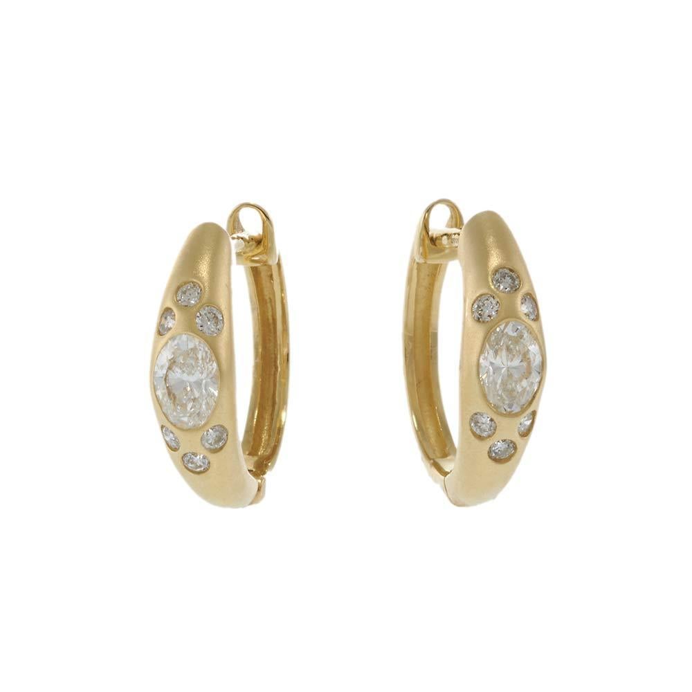 Bold meets refined in these contemporary 14KT yellow gold huggie hoop earrings. Featuring a blend of round and oval diamonds in a bezel-style flush setting, the design offers a striking contrast of shapes and brilliance. With a total diamond weight
