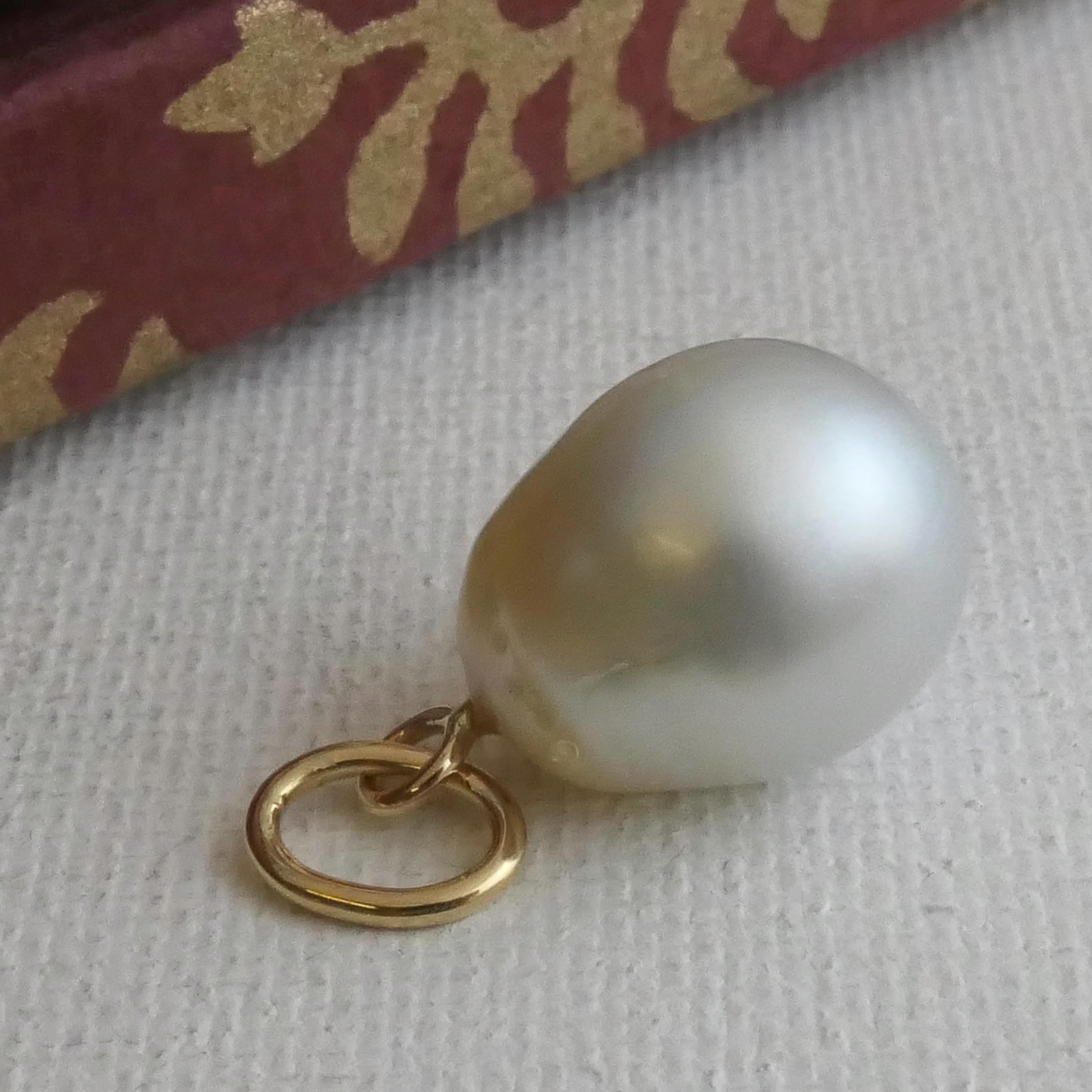This elegant pendant showcases a luminous 12x15mm South Sea pearl, celebrated for its naturally lustrous, creamy white hue and subtle golden undertones. The drop shape of the pearl adds a touch of organic beauty, making each piece unique. Known for
