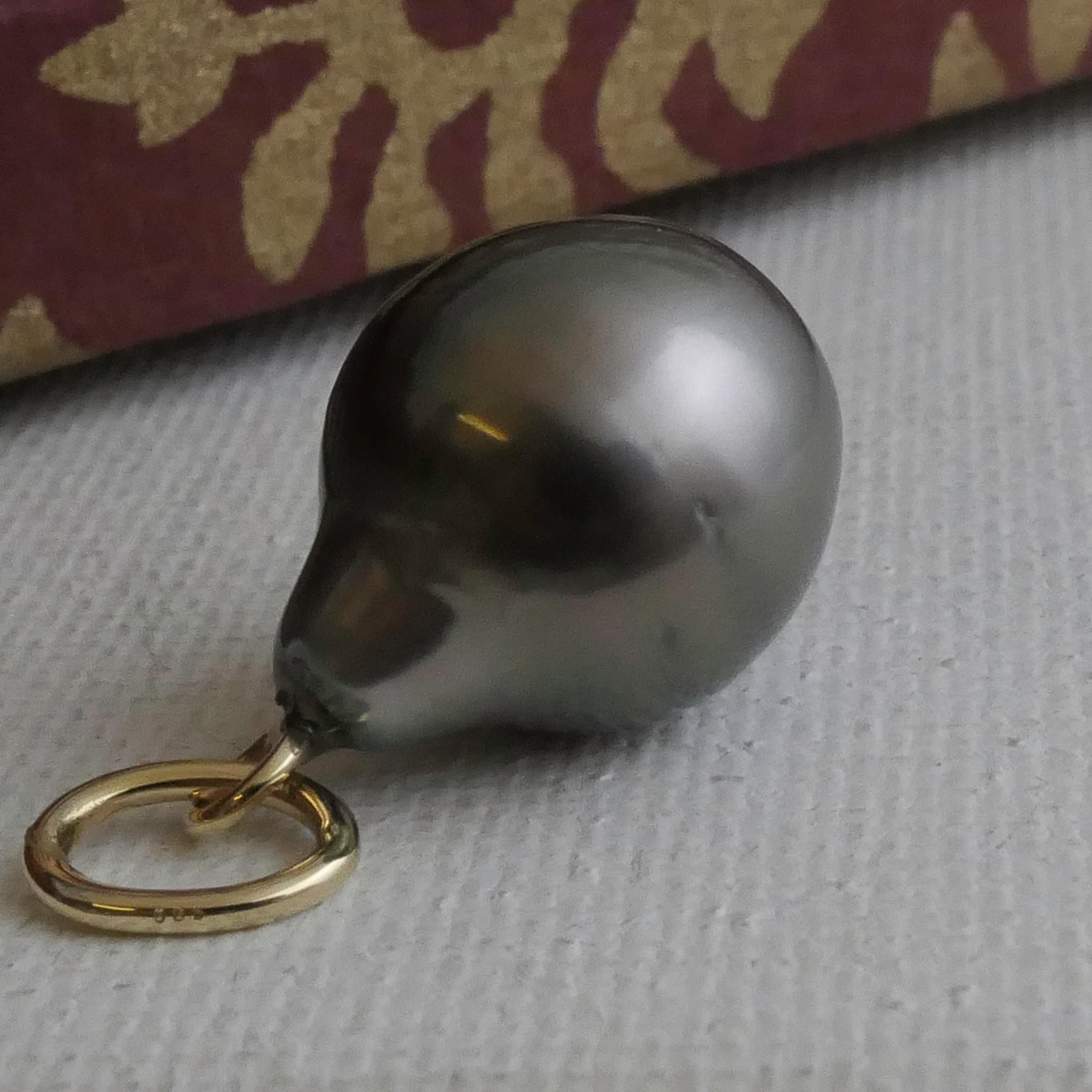 This pendant features a stunning Tahitian pearl, known for its luxurious dark luster and unique teardrop shape. Measuring 12x16mm, the pearl displays a deep, multi-tonal hue with an iridescent sheen that ranges from shades of silvery gray to hints