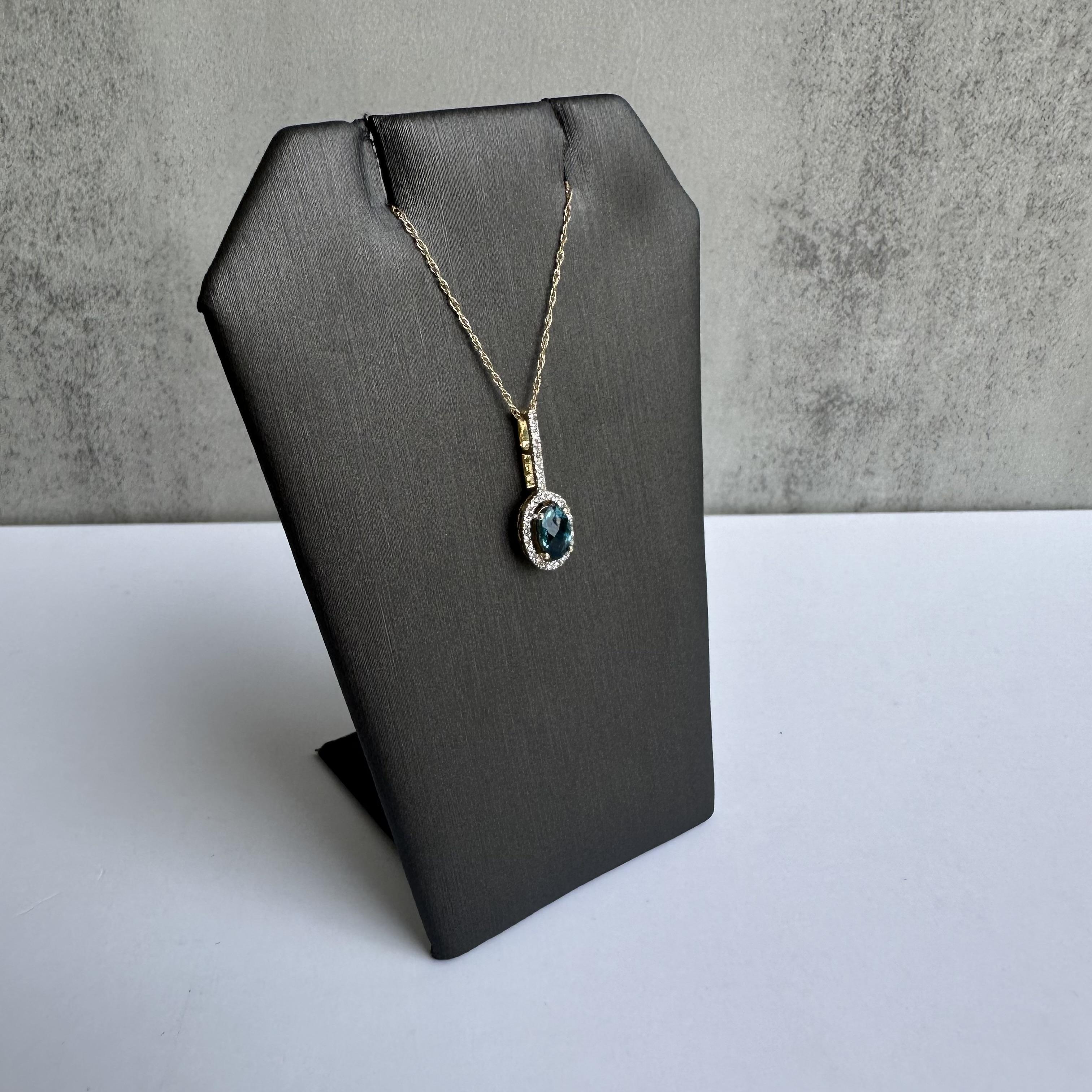 Enhance your jewelry collection with this stunning Topaz and Diamond Necklace in 14kt Yellow Gold. Featuring a captivating 5.9x4mm oval London blue topaz with a faceted top and 0.10 carats of GH SI natural round single cut diamonds, this necklace is