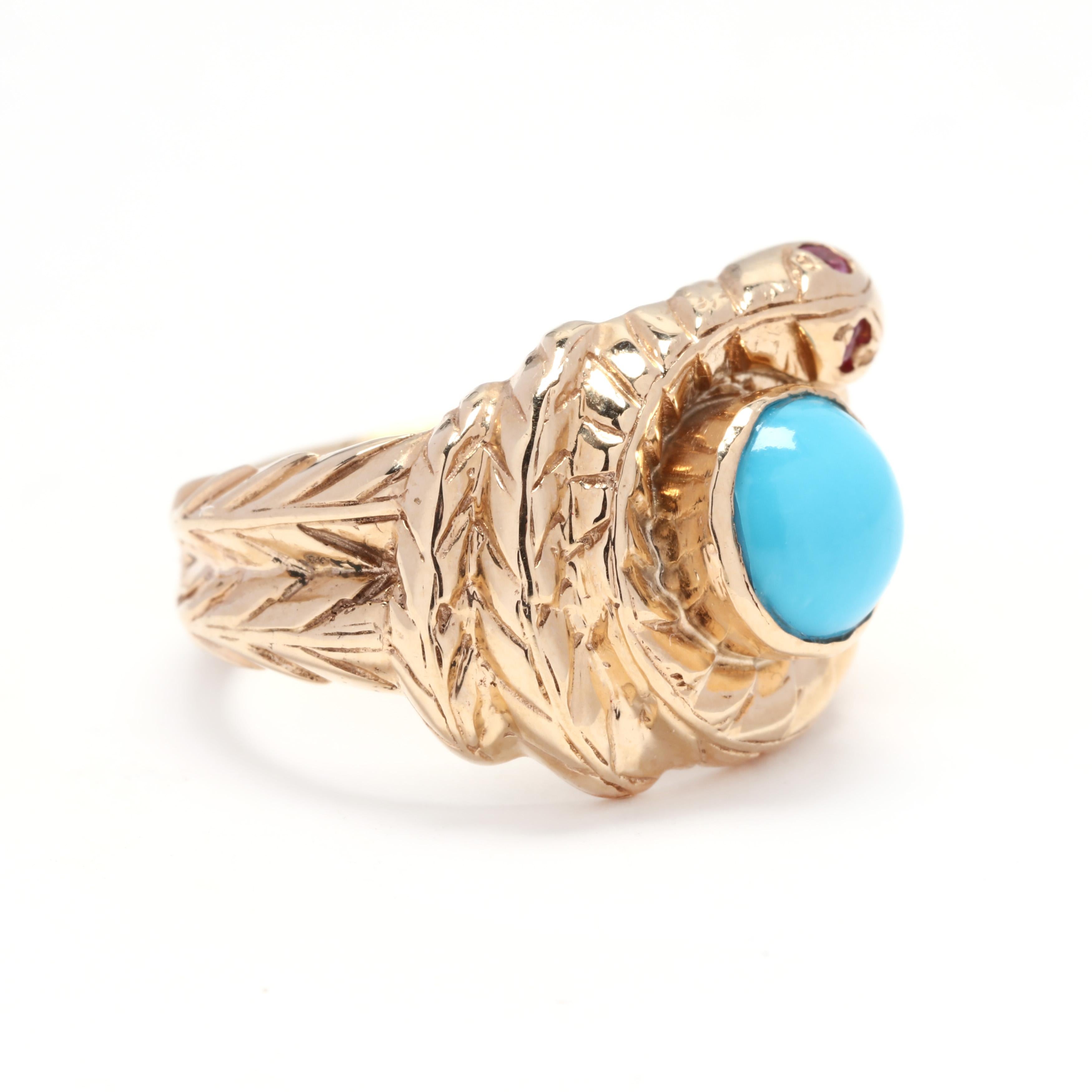 A 14 karat yellow gold, turquoise and ruby coiled snake ring. This ring features a textured coiled snake design centered around a bezel set round cabochon turquoise stone and with two round cut rubies for eyes.

Stones:
- turquoise, 1 stone
- round