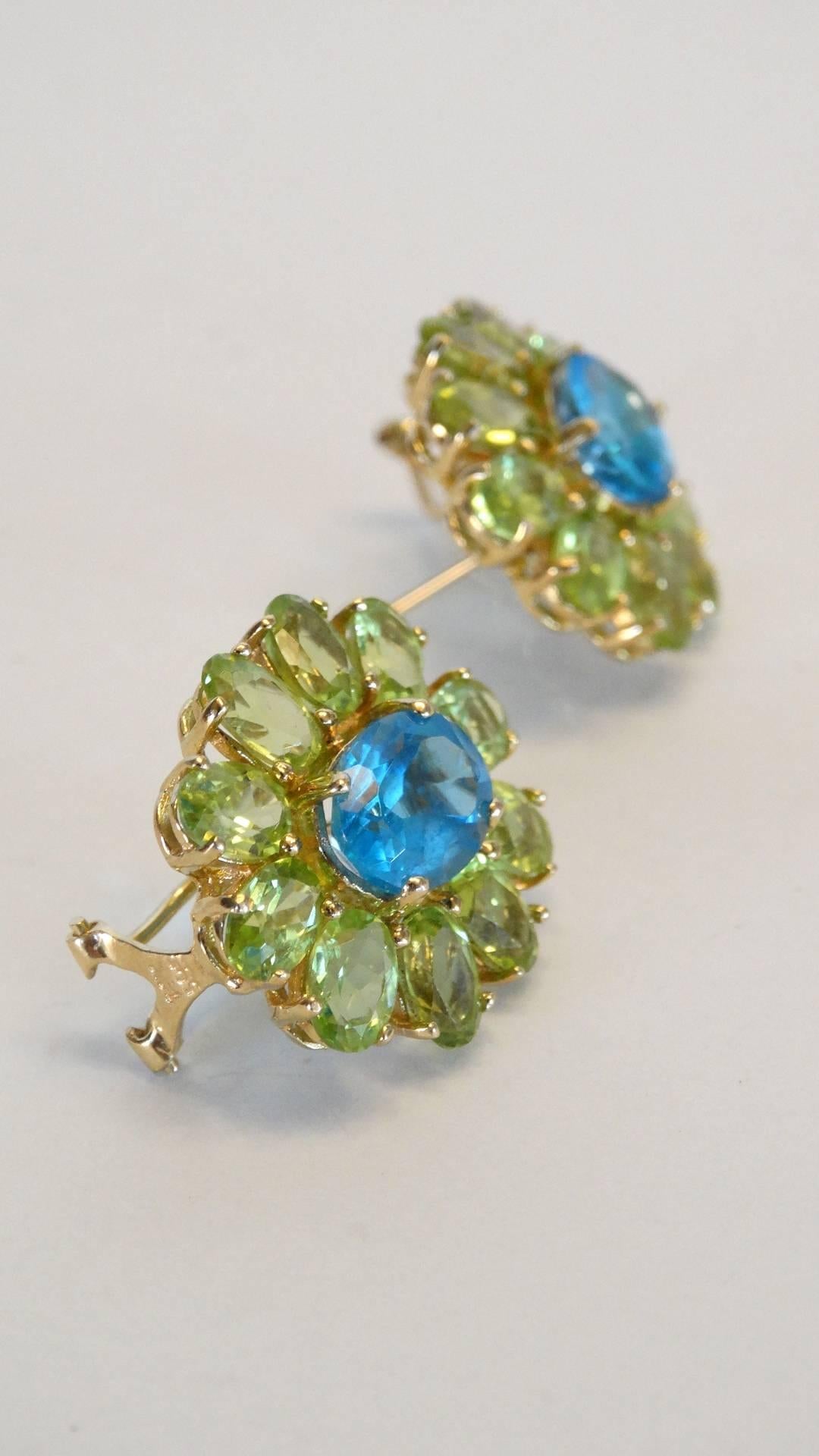 Stunning vintage flower earrings created with bright blue topaz and green peridot, set in 14kt yellow gold. A beautiful color combo signed 585 with a hallmark stamp of a heart. Designer unknown for pierced ears only 