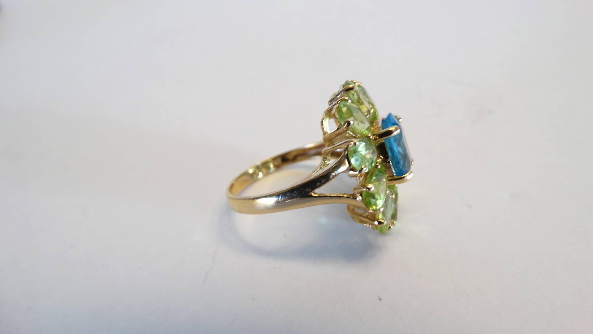 Stunning vintage flower ring created with bright blue topaz and green peridot, set in 14kt yellow gold. A beautiful color combo signed 585 with a hallmark stamp of a heart. Designer unknown ring size 8 