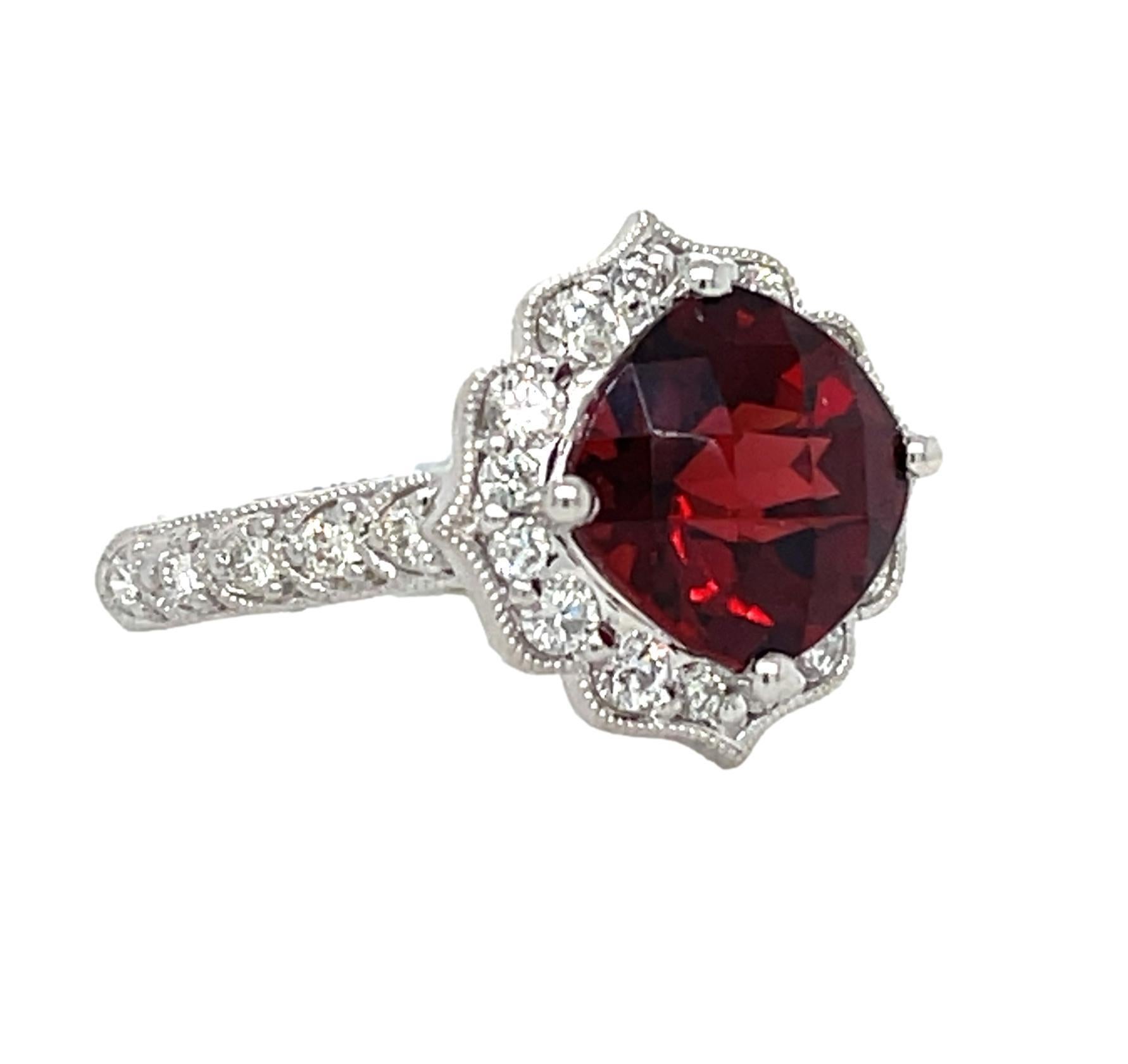 This stunning ring has a 9x9mm checkerboard cushion Garnet set in 14 karat white gold. There are 26 shimmering diamonds around the center stone and on the shank for a delicate accent. This ring will be shipped in a beautiful box, ready for the