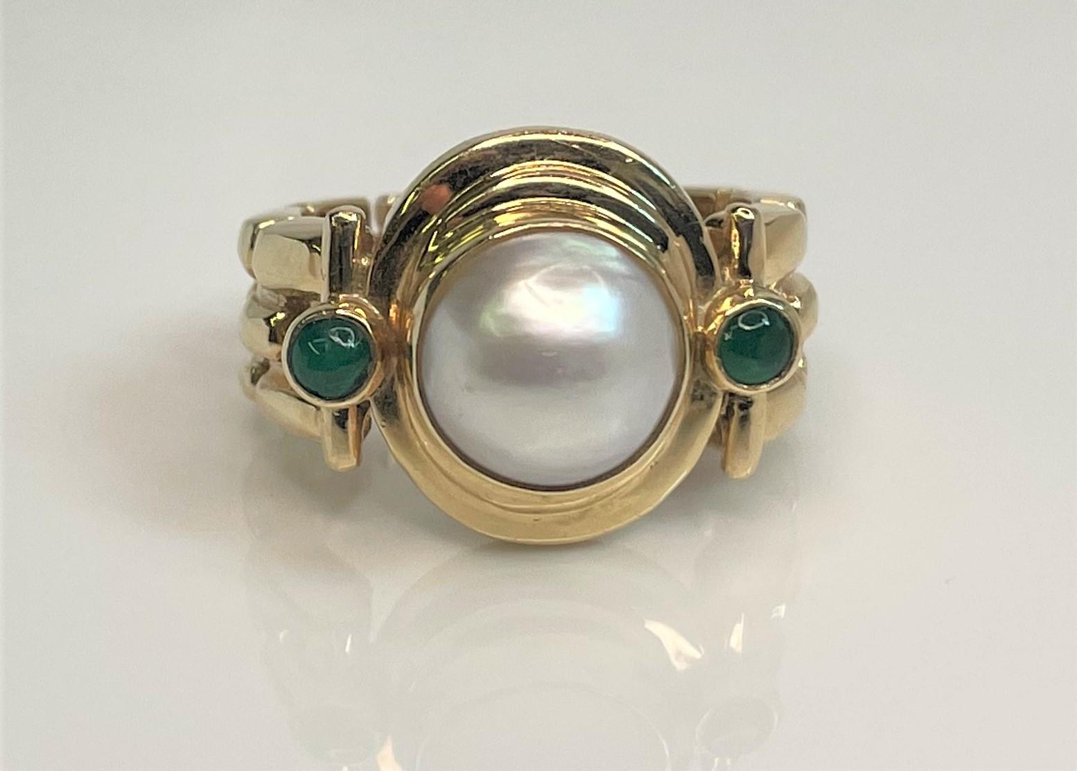 Beautiful 14 karat yellow gold 'chain link' design band with round head.
8.5-9.0mm cultured mabe light grey pearl center.
2 round cabochon emeralds on each side of pearl center.  
Stamped 