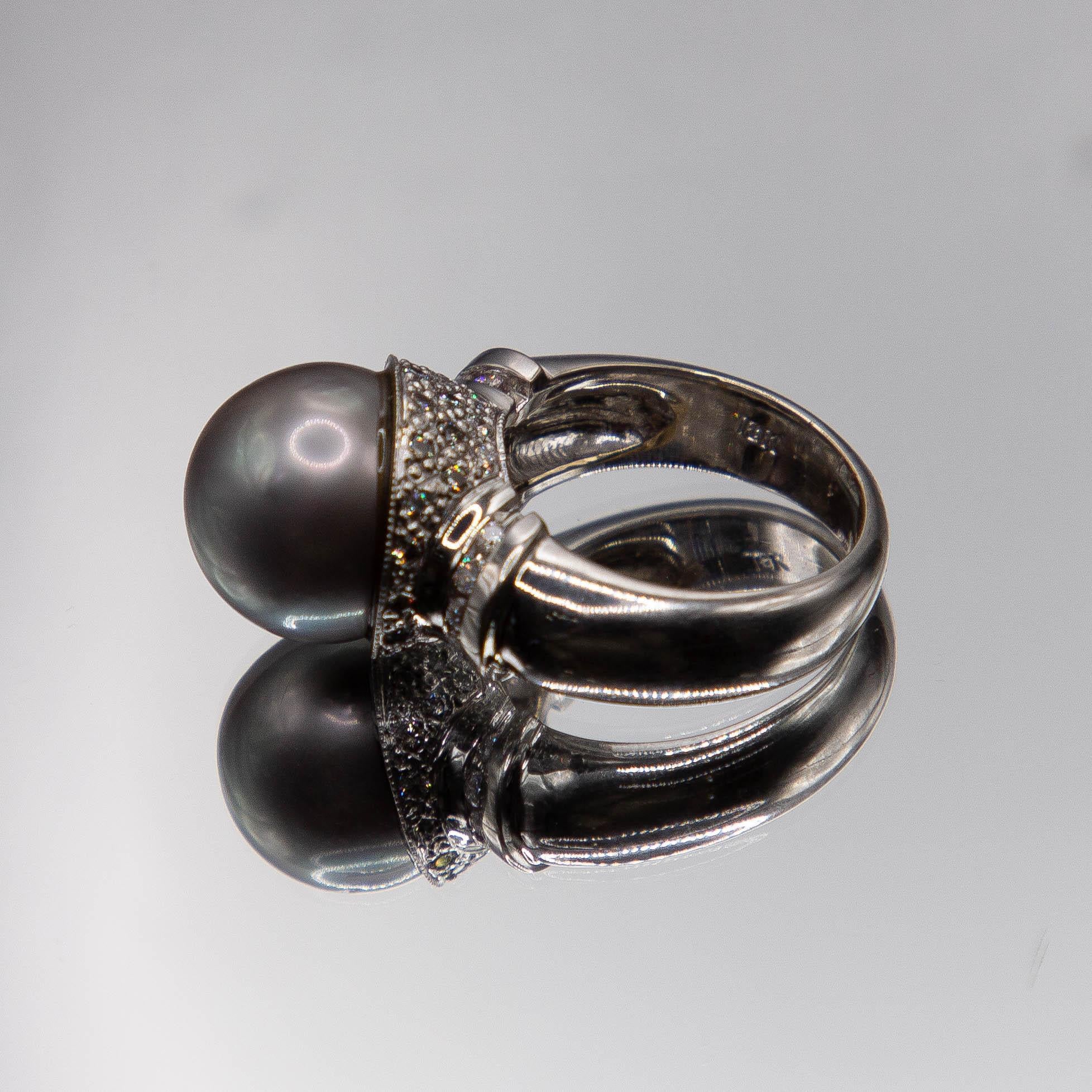The high polish 18k white gold ring features a fine 14mm Tahitian South Sea pearl. Center gem has very good roundness, very high luster, strong orient, good blemishing, thick nacre,  body color of a slate grayish- black and Peacock overtone . The