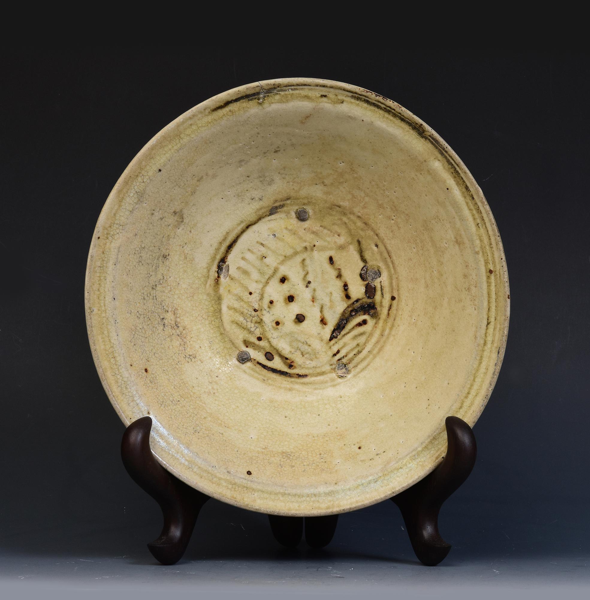Antique Sukhothai glazed ceramic fish dish.

Age: Thailand, Sukhothai Period, 14th - 16th Century
Size: Diameter 23.8 C.M. / Thickness 8.2 C.M. (size excluding stand)
Condition: Nice glaze and condition overall (natural minor cracks on the