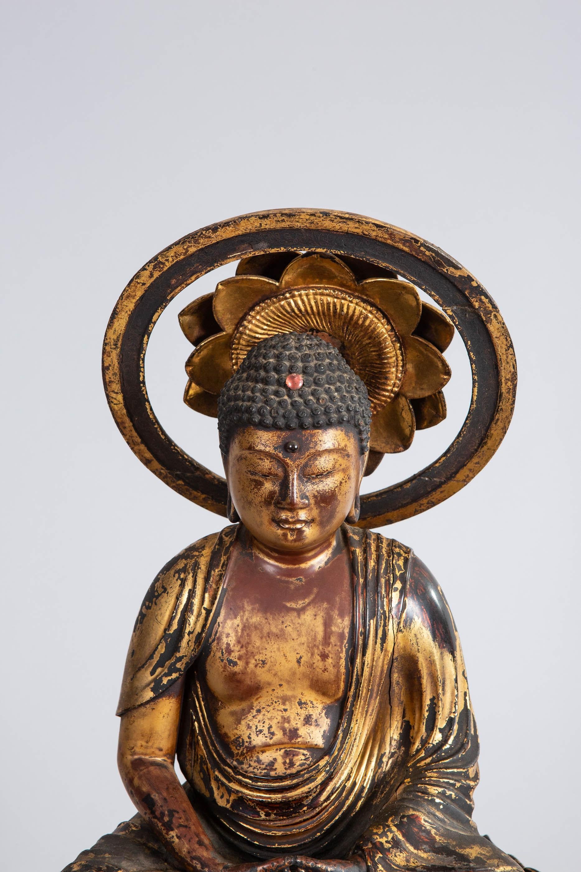 Hand carved wood with gesso and gold, Amida Buddha sitting on a lotus blossom with halo. In remarkably excellent condition. No visible restoration, has both original stones on third eye and crown chakras. Early Muromachi period (1333-1573). From the