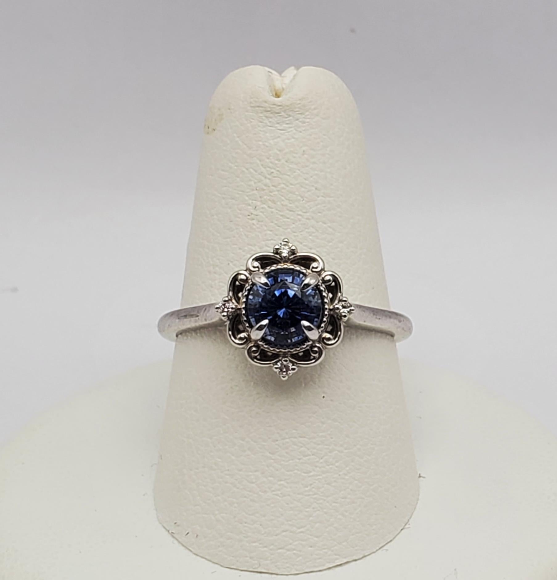 Gorgeous natural blue sapphire and diamond vintage style ring. This ring features a vibrant round brilliant cut 0.85ct blue sapphire and four round brilliant cut diamonds with a total weight of 0.04cts. The mounting design has a cathedral style