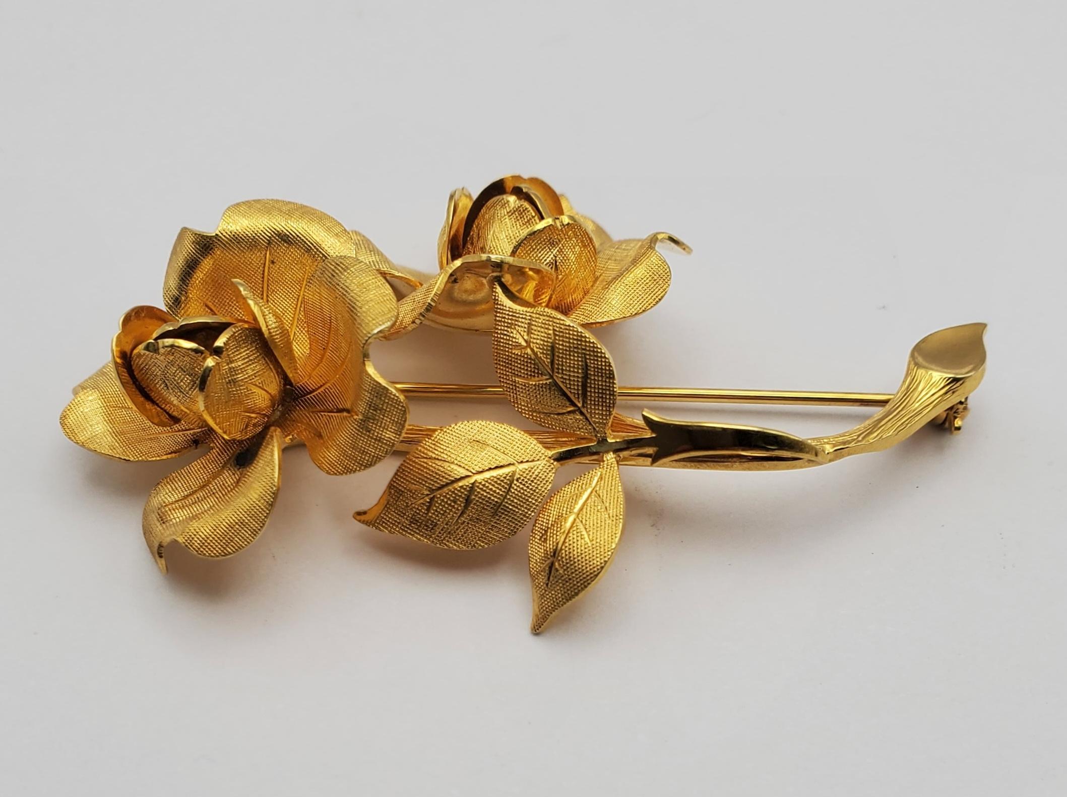 Exquisitely detailed Tiffany & Co. brooch featuring two roses in bloom crafted in 14k yellow gold. The natural beauty of the flowers is rendered wonderfully with even the veins of the leaves visible. The back of the pin features c-lock mechanism for