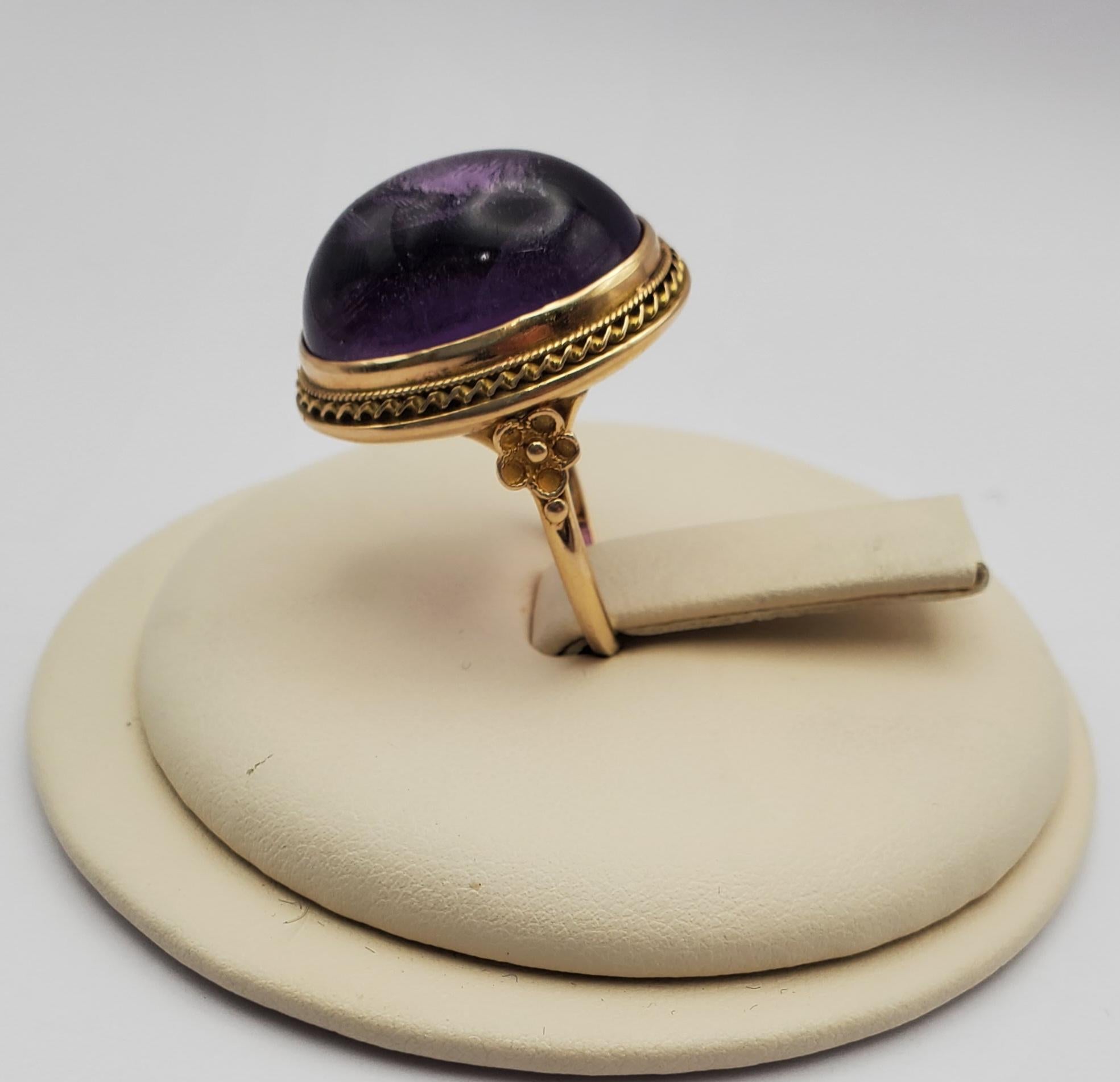 Gorgeous large 28.57ct Amethyst cabochon vintage ring. The richly colored stone is set in a bezel with carved and floral details. Its a statement piece perfect for purple lovers and people with an appreciation for bold jewelry looks. The ring is