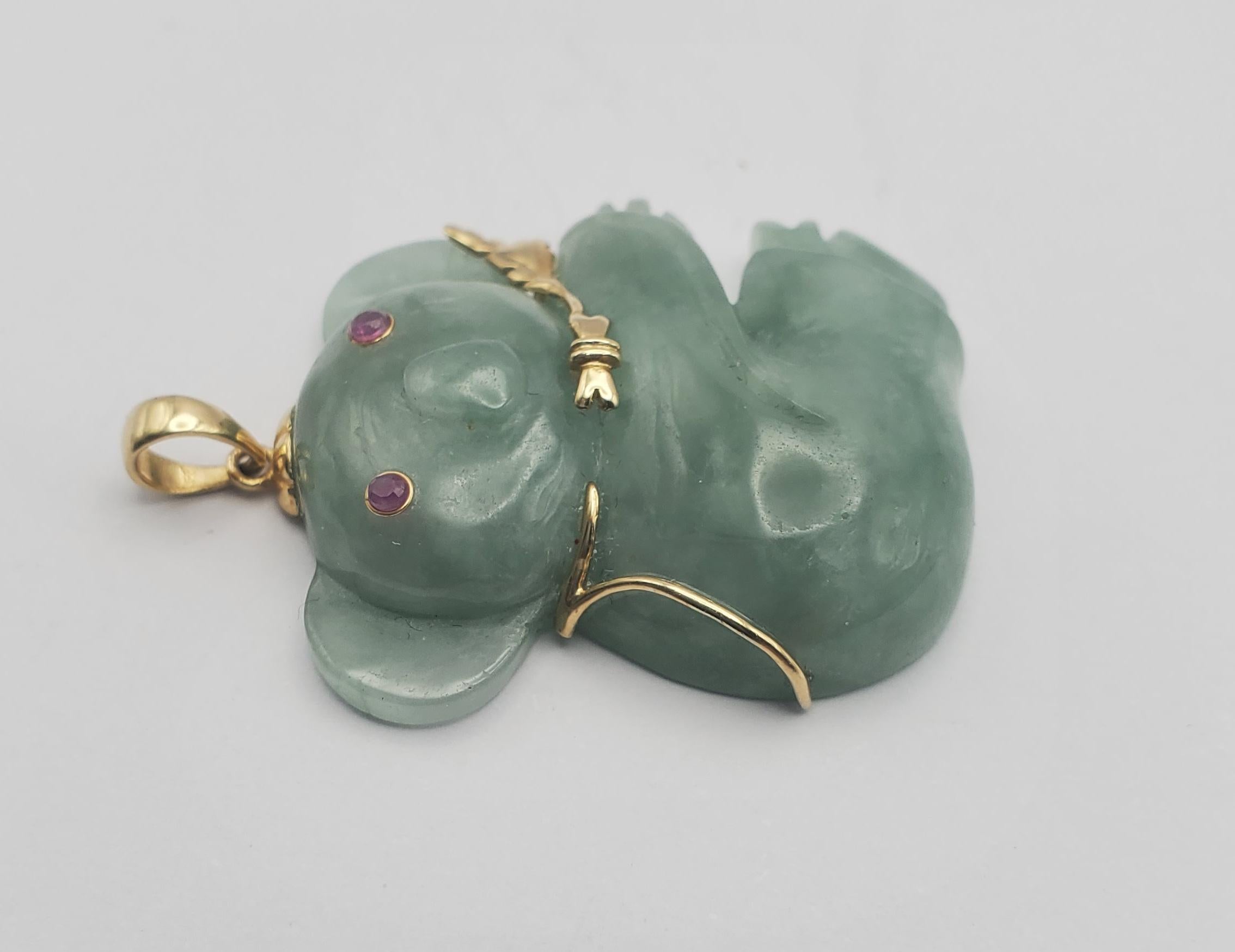 Charming carved jadeite koala pendant with 14k yellow gold and ruby accents. The jadeite is a pretty sage green color, green with blue undertones, that looks refined when combined with the yellow gold. The koala features bezel set round ruby stones