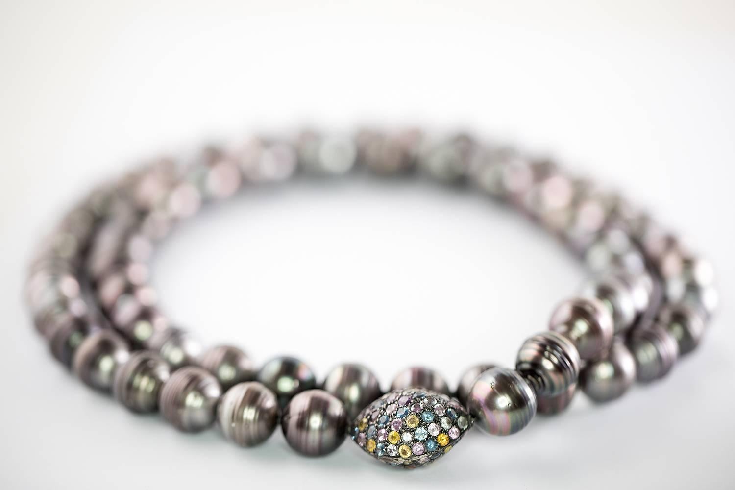 Round Off Shape, One of a Kind, Black Tahitian Cultured Pearls 15 - 17.5mm of blue and pink overtones and high luster set as a Long Necklace 100cm featuring an oval 925 Sterling Silver bead pavé with multi colored natural Sapphires of blue, pink,