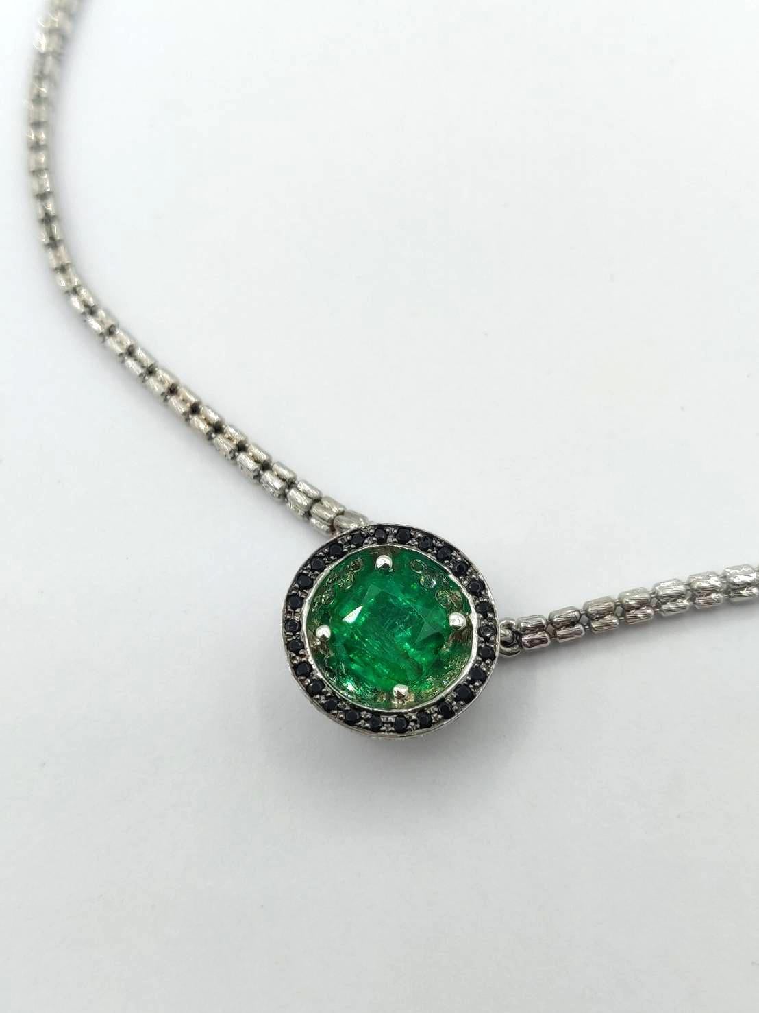 Dieser Anhänger besteht aus einem lebendigen Smaragd im Kissenschliff von 1,5 Karat auf einer konkaven, mit weißen Diamanten verzierten Oberfläche, die von schwarzen Diamanten akzentuiert wird. Die andere Seite ist eine Halbkugel mit weißem