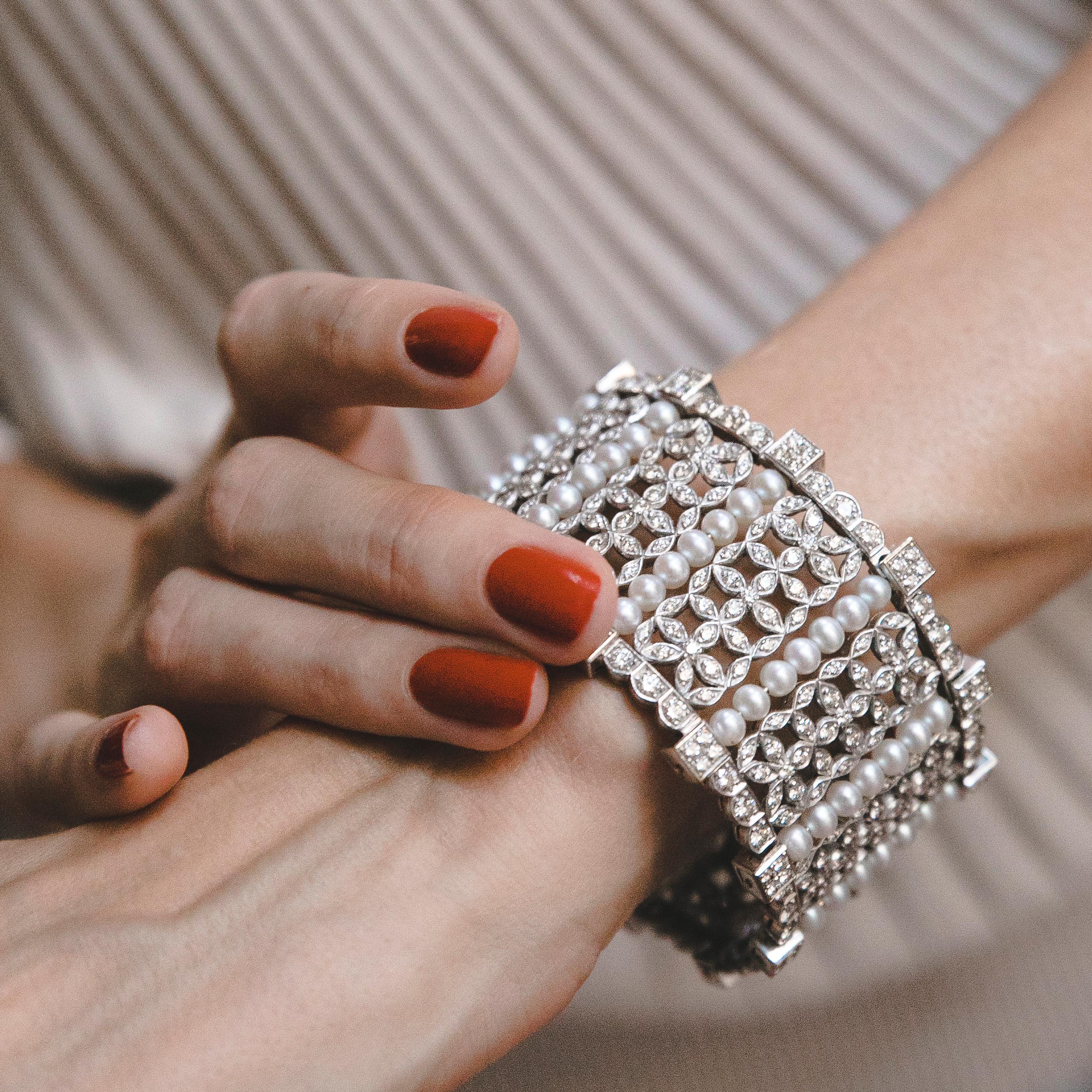 Diamonds Pearls White Gold Bangle Bracelet. Really fine item. Lines of Pearls divide the links of floral ornamentation. Top and bottom lines incorporate fine round-cut Diamonds weighing in total 15 Ct. There is an extra lock on top for security. The