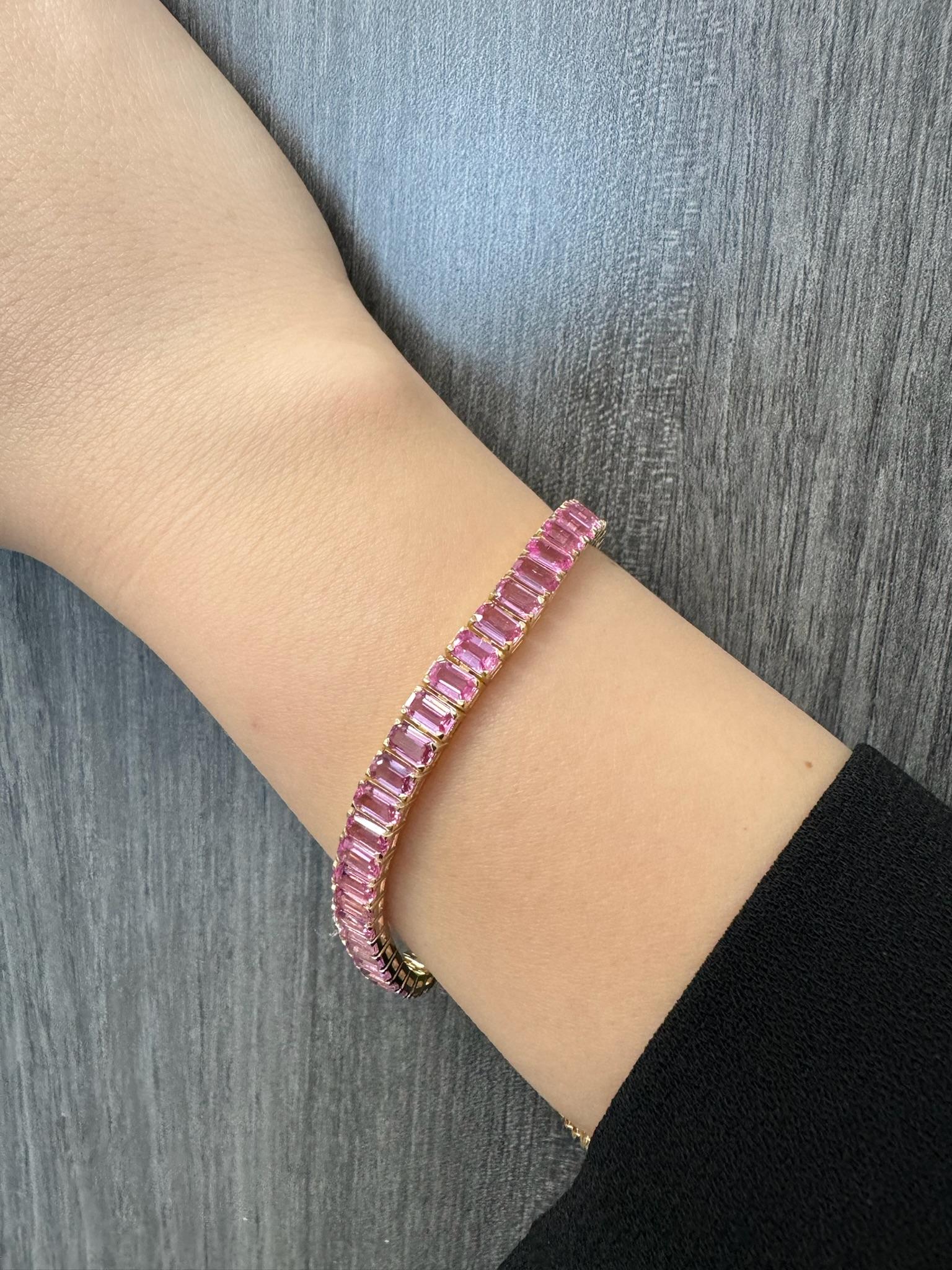 Dieses wunderschöne Tennisarmband aus 14-karätigem Gelbgold mit Smaragdschliff und rosa Saphir wird Ihnen sicherlich den Atem rauben. Mit seinen wunderschönen 15 Karat rosafarbenen Saphiren, die in Smaragdform geschliffen sind, schmückt er anmutig