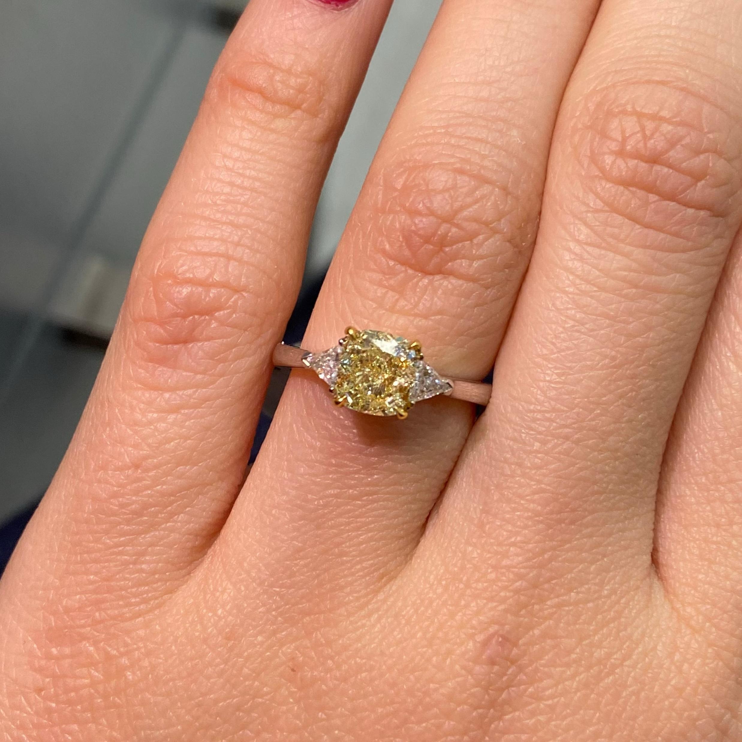 This 1.5-carat Fancy Yellow cushion-cut diamond engagement ring is a truly unique and elegant choice for celebrating your love story. The GIA-certified center diamond showcases a radiant yellow hue and exceptional clarity, making it a standout