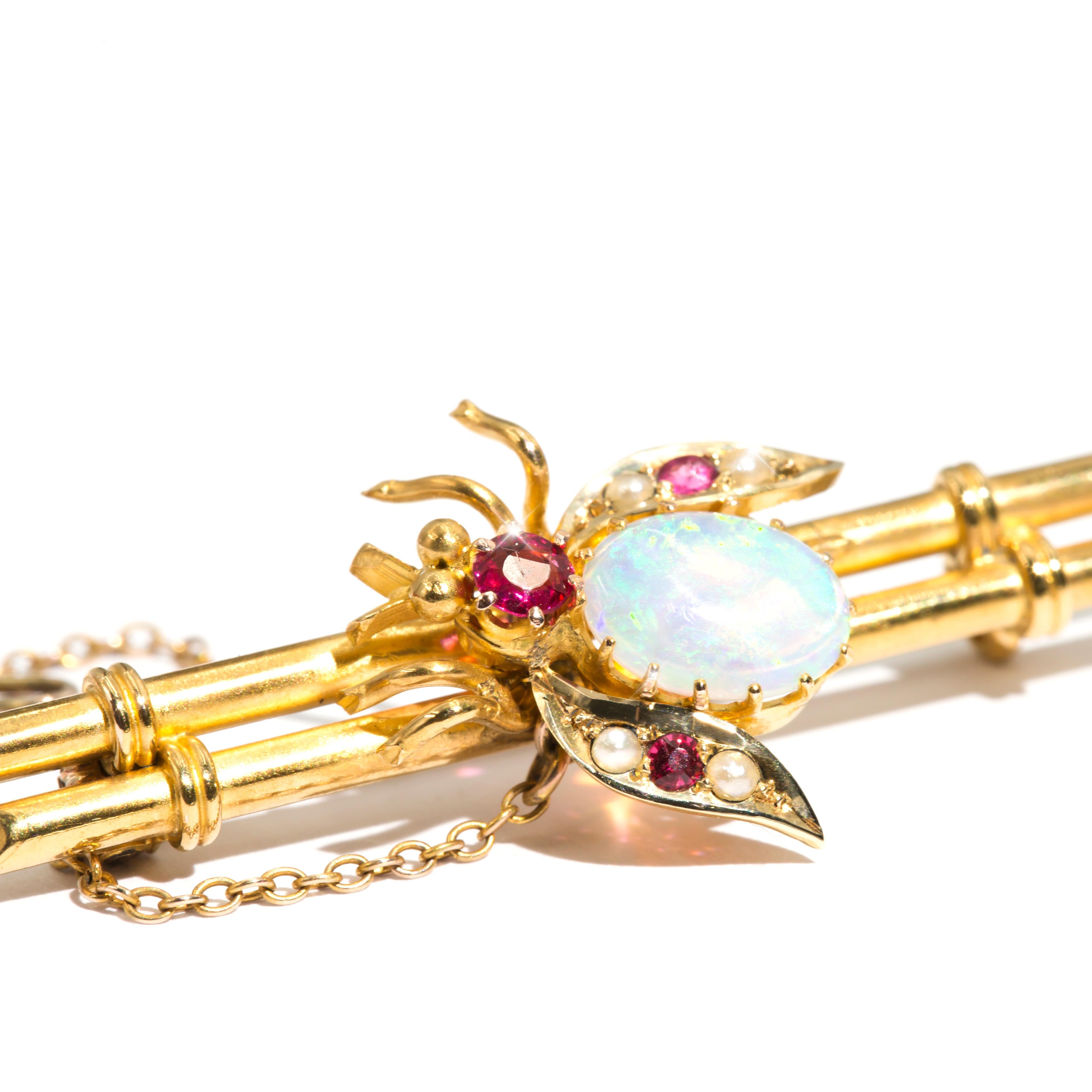 Carefully crafted in 15 carat gold is this gorgeous antique Edwardian brooch, Circa 1910, features a central bee with a solid oval crystal opal forming the body, and round pinkish-red garnet topped doublets with tiny little seed pearls in the wings.