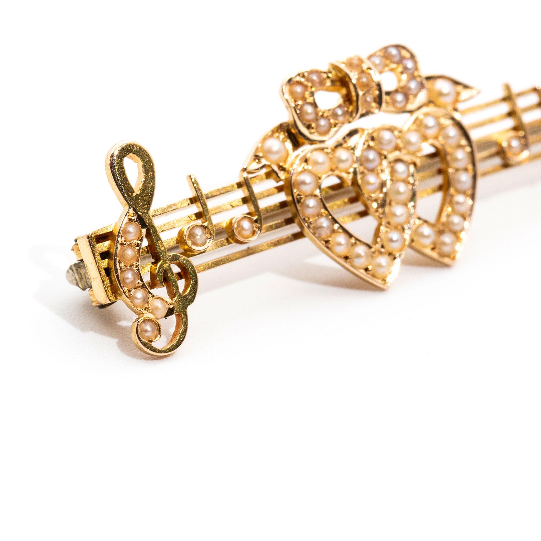 Carefully crafted in 15 yellow gold is this antique Victorian bar brooch, circa 1900s, which features two hearts tied with a bow and carefully set with seed pearls. The tied hearts symbolise the connection of love between two people, being between