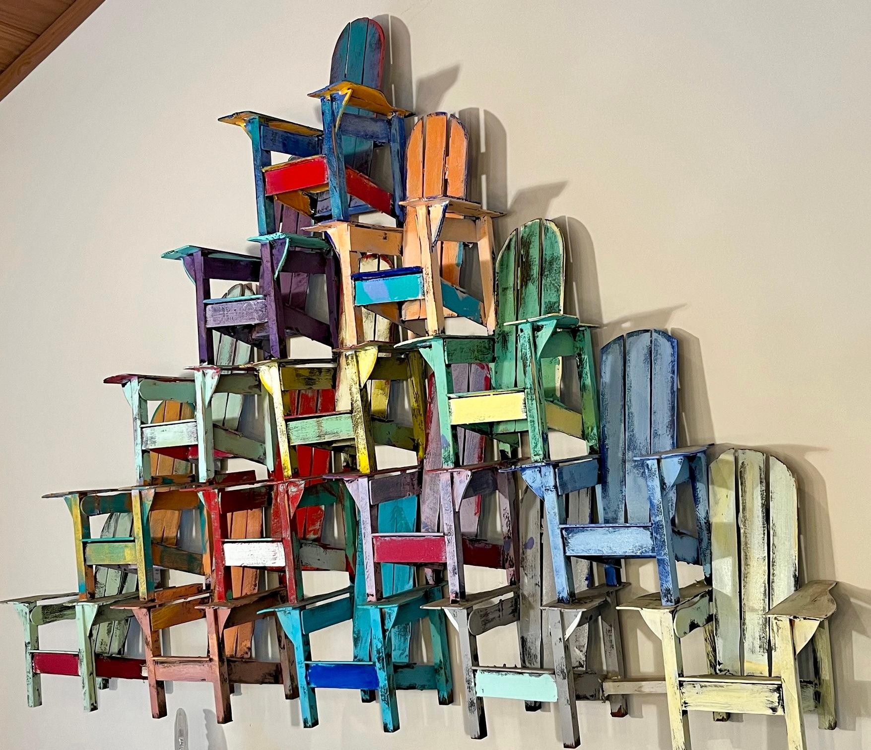 A colorful three dimensional painted wood model of stacked Adirondack chairs.  These wall sculptures by Paul Jacobsen are instant conversation pieces.  

Paul Jacobsen used everyday objects, such as chairs, cars, airplanes, trains, motorcycles and
