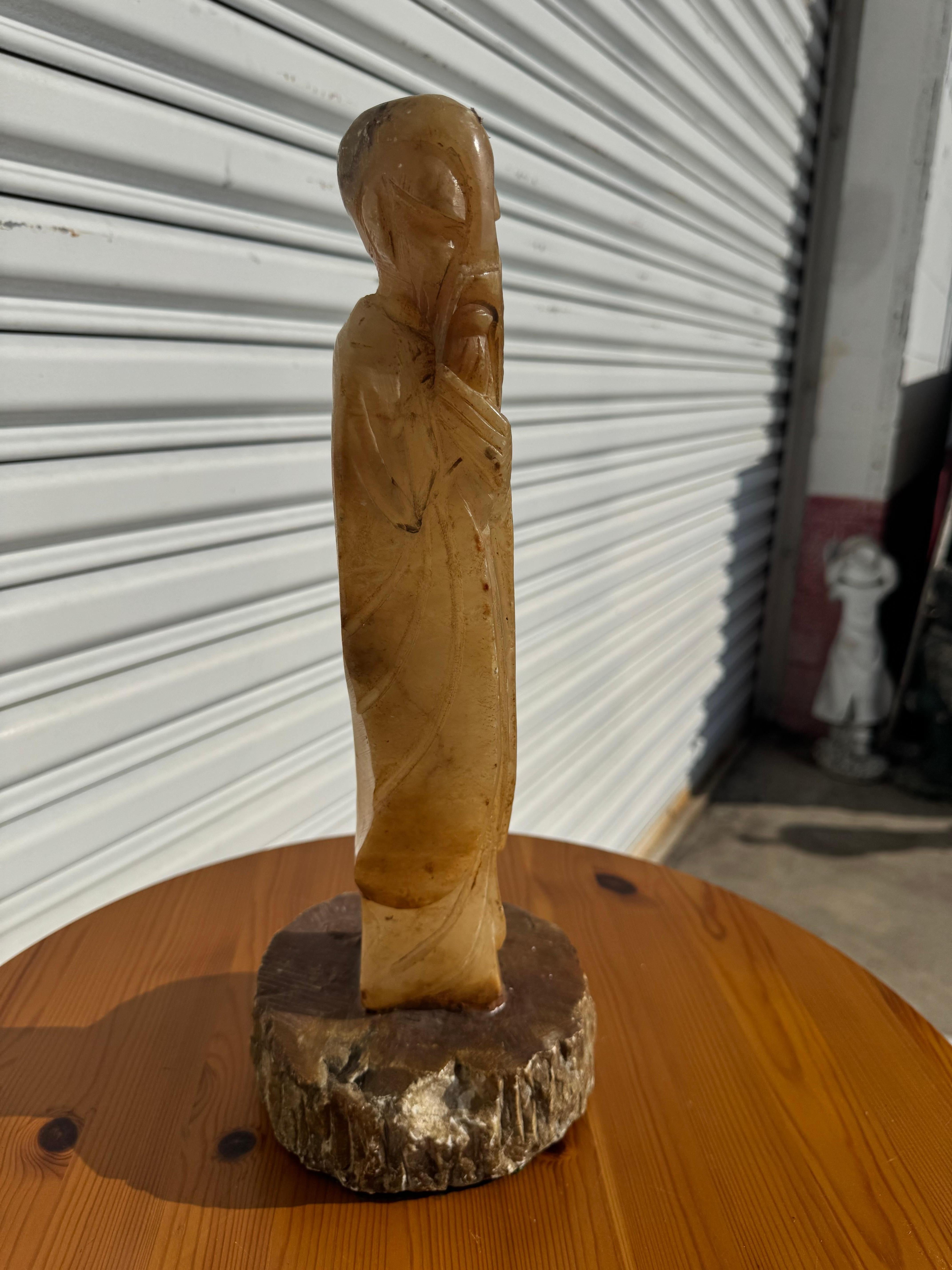 This is a stone sculpture depicting a pious Monk.
The base is formed out of stone also. 