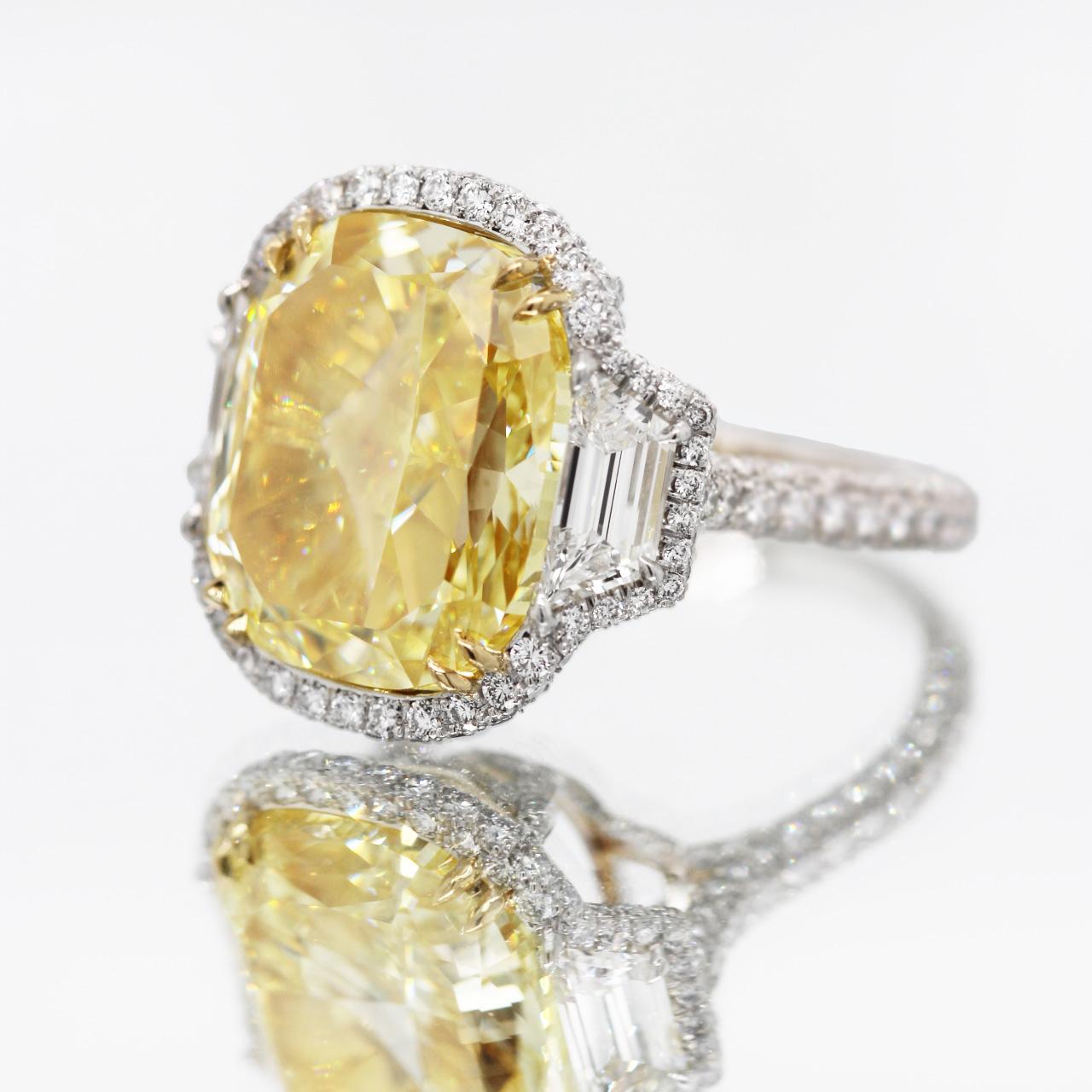 GIA-certified 15+ carat Fancy Intense Yellow cushion-cut diamond three-stone engagement ring. Trilogy ring feature a 15.15 carat natural, Fancy Intense Yellow cushion-cut center stone, set on 18 yellow gold and platinum. 

A halo of white melee