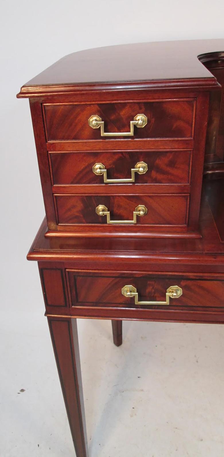 A fine mahogany Carlton House desk with 12 fitted drawers in the upper case over three fitted frieze drawers below the writing surface. Each drawer has crotched mahogany veneer fronts, as well as solid brass drawer pulls, and the desk is supported