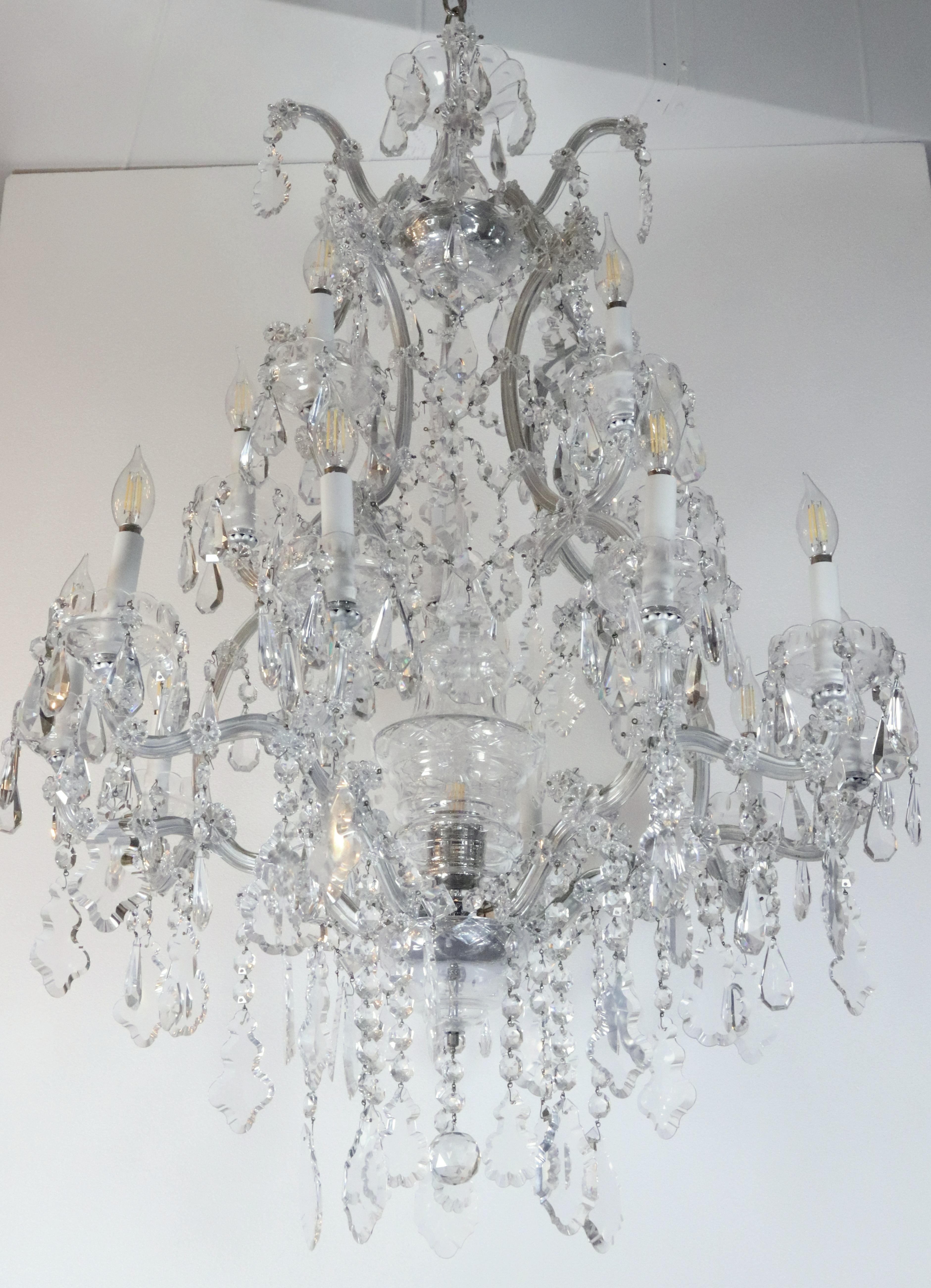 Lampadario in stile Marie Therese della metà o della fine del XX secolo con cristalli a forma di ottagono, goccia, rosetta floreale e pendolo e i suoi caratteristici bracci in vetro curvo. Presenta una catena e un baldacchino con finitura cromata.