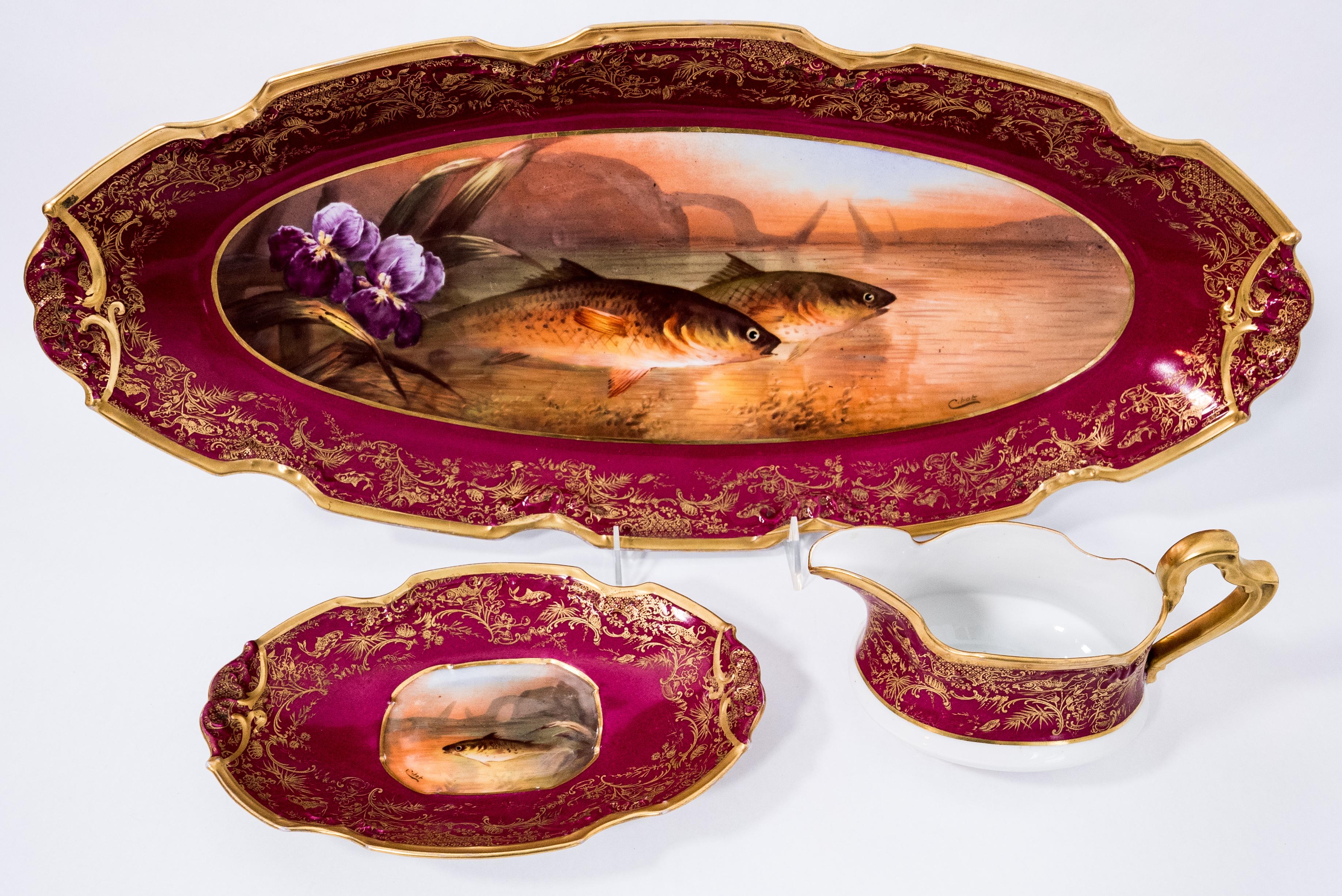 A great last quarter 19th century Limoges France fish service featuring rich ruby ground, a highly shaped form and hand painting. The pieces are artist signed and have beautiful orchid and full flora fauna backgrounds. We love the vibrant color of