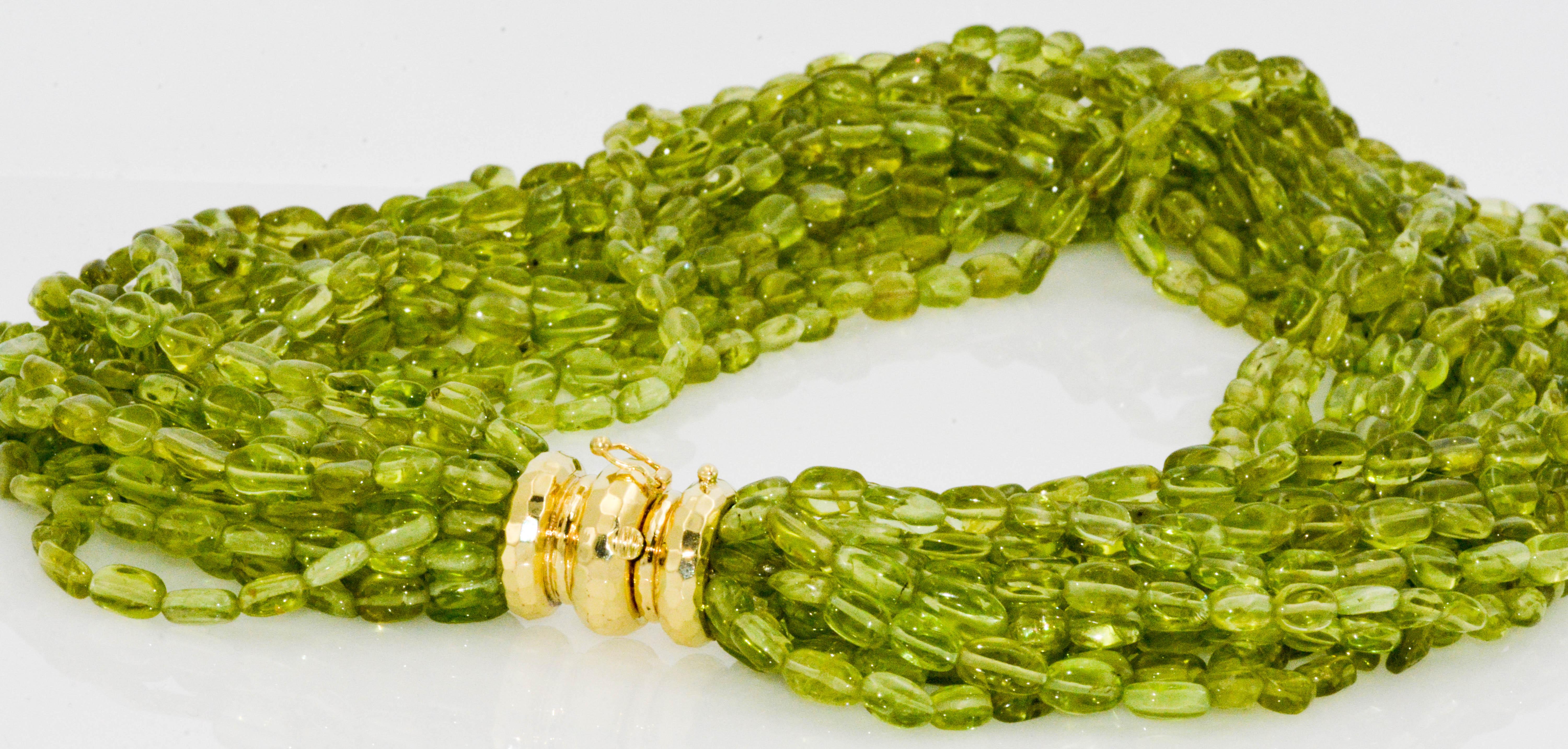 This 18 inch multi-strand Torsade Peridot necklace is pretty enough to be a scarf. Oval beads averaging 7.25 mm are strung on 15 strands and attached with a beautiful 18 karat yellow gold clasp that you won't want to hide. Circa 1980.