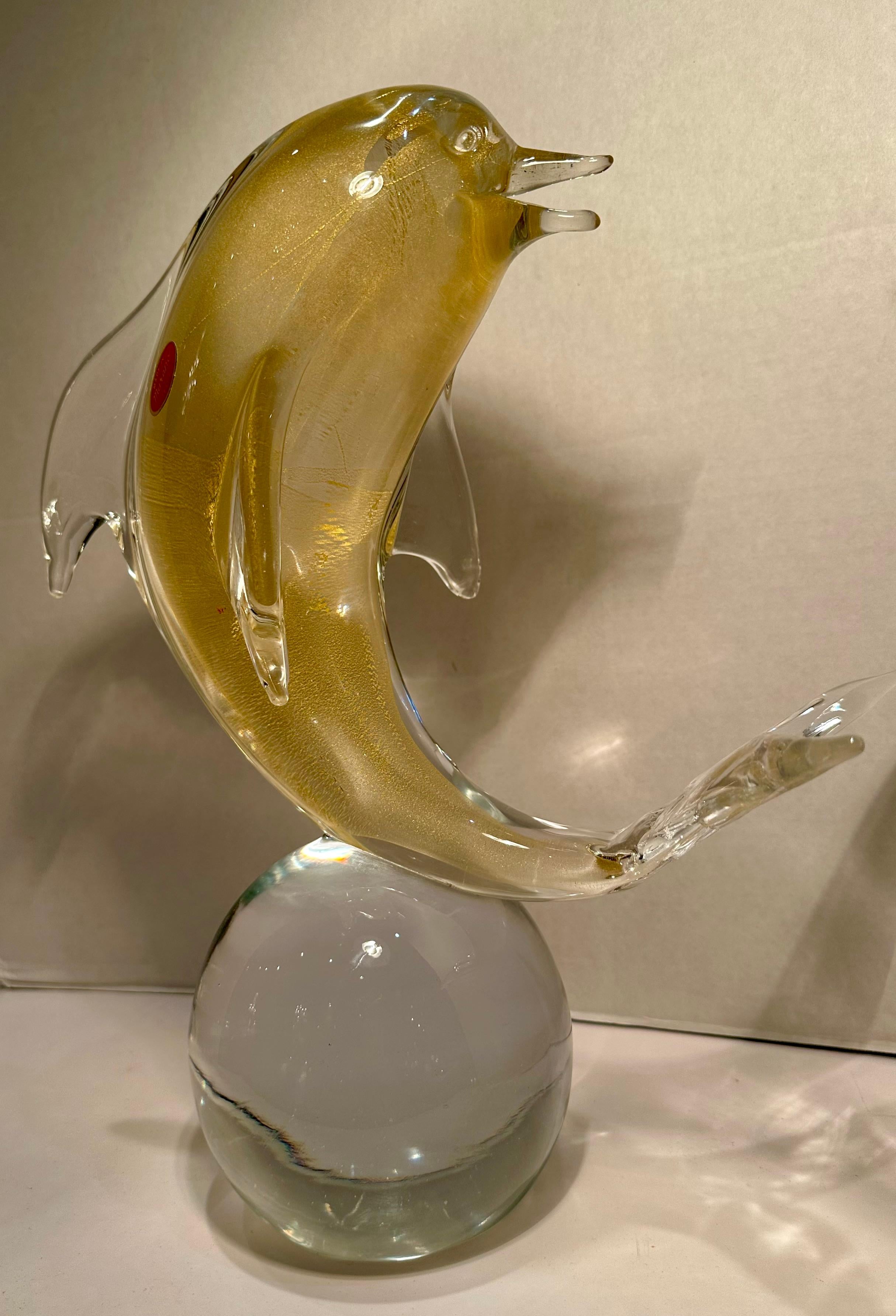 Très impressionnante, fabriquée à la main et soufflée à la bouche en Italie, la sculpture en verre d'art de Murano capture la beauté d'un dauphin en équilibre sur une boule ou une sphère transparente. L'artiste a ajouté de l'or 24 carats pour créer