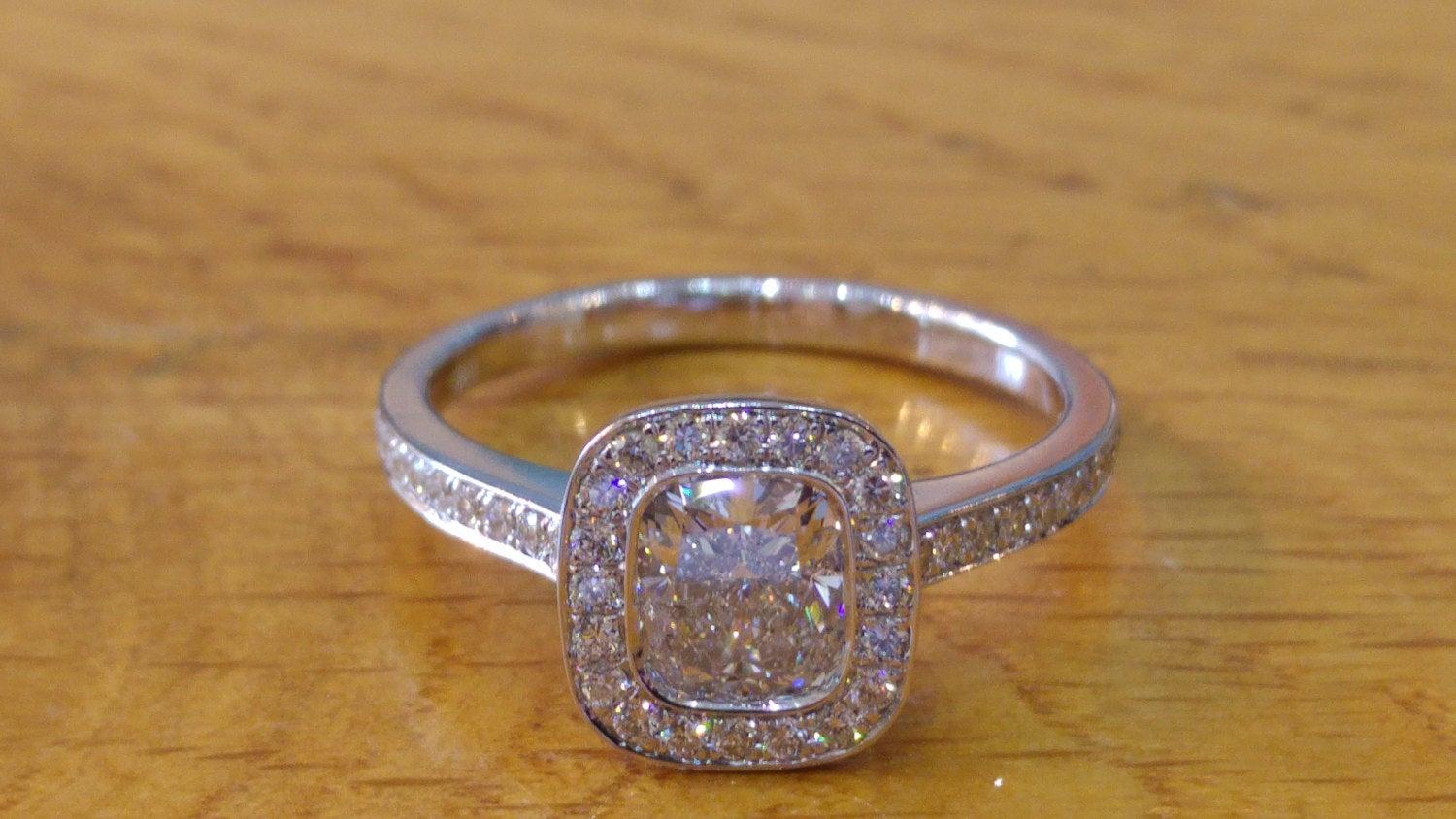 A beautiful cushion diamond halo engagement ring made of 14K white gold bezel set with a beautiful diamond of 1.00ct (can be set with any stone size) accented by white round diamonds. The center diamond of this classic gold ring is of Excellent cut,