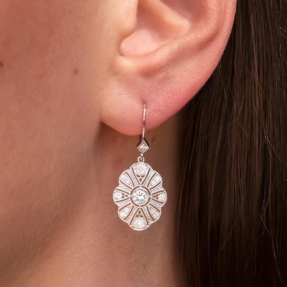 These elegant and brilliantly sparkling diamond earrings bring the glamour with a chic and sophisticated Art Deco style design! The 0.70ct center diamonds are bright white, completely eye clean, and stunningly vibrant. The setting is encrusted with