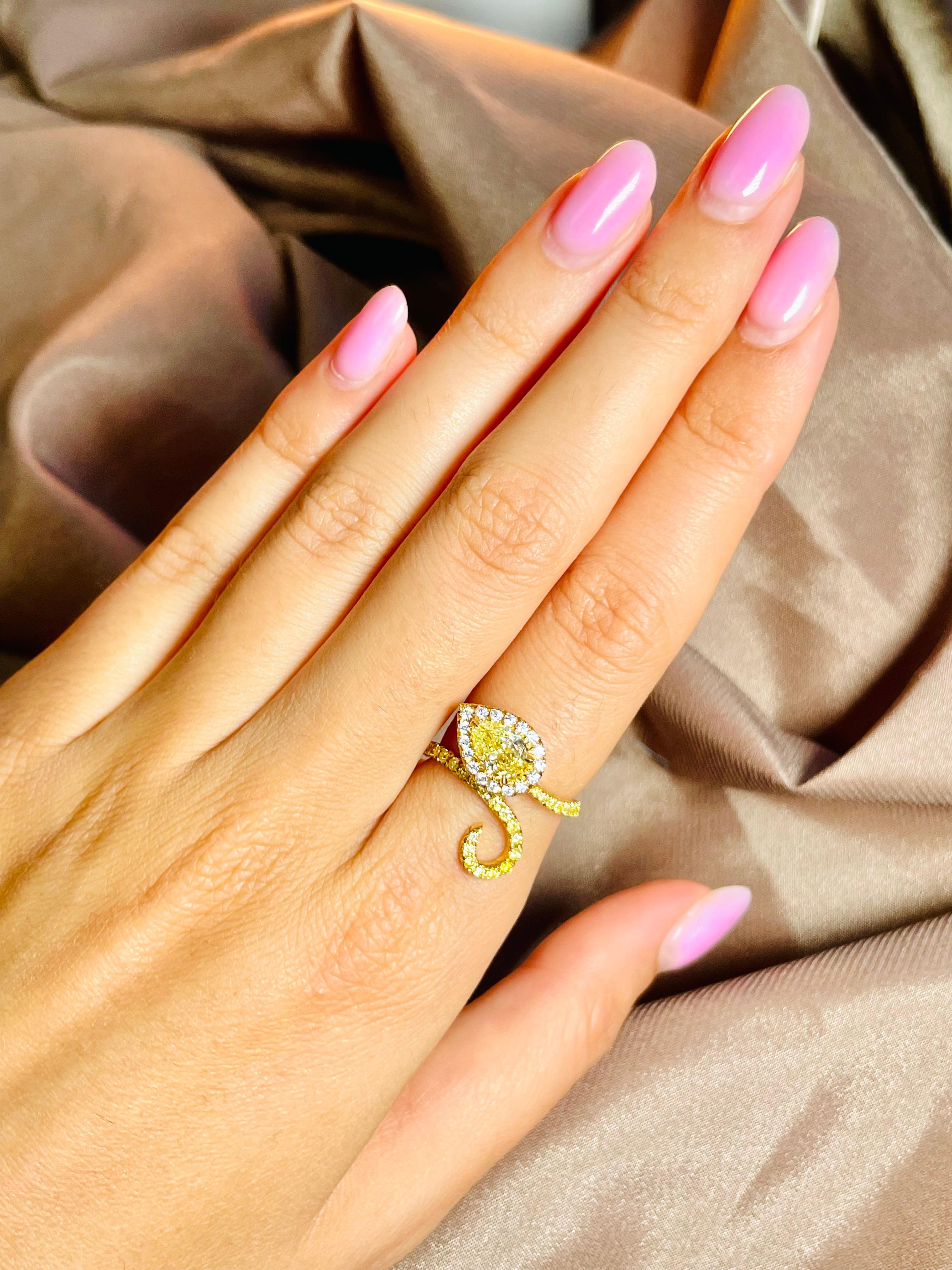 Cette bague serpent diamant unique met en valeur un remarquable diamant jaune fantaisie de 1 carat en forme de poire certifié GIA, d'une pureté de VS2. La pierre centrale captivante est entourée de 17 diamants blancs ronds et brillants, complétés