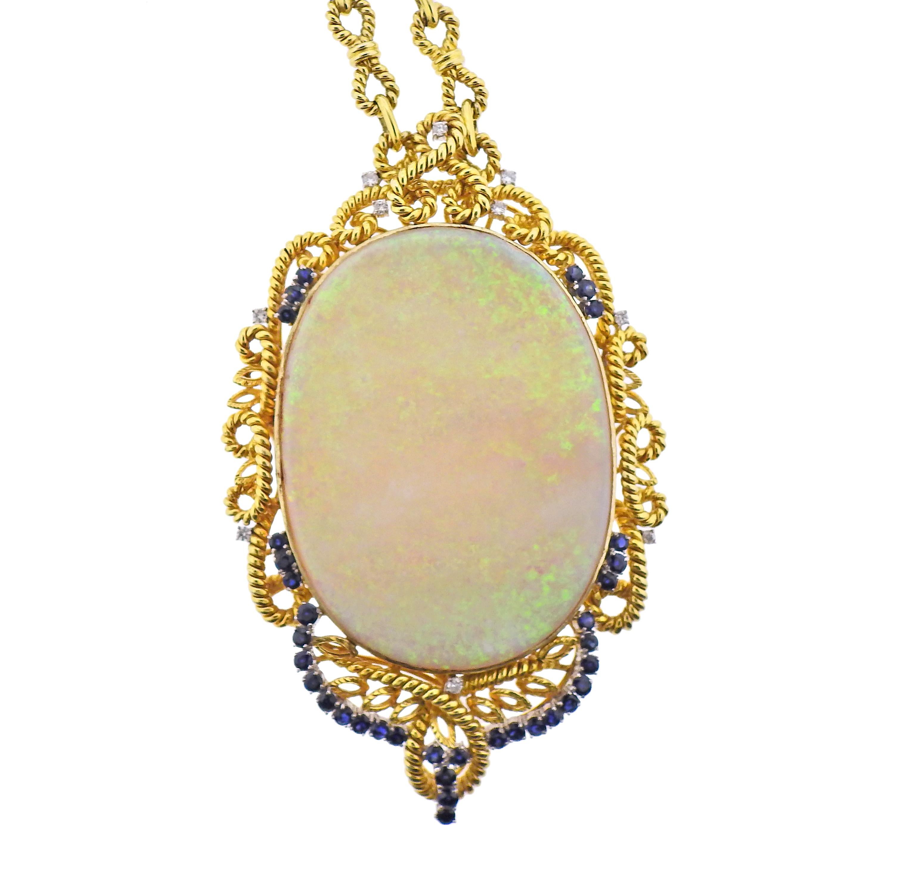 Massive 14k gold pendant necklace, featuring approx. 150ct opal (measures 74 x 55mm), surrounded with sapphires and approx. 0.50ctw in diamonds. Necklace is 29