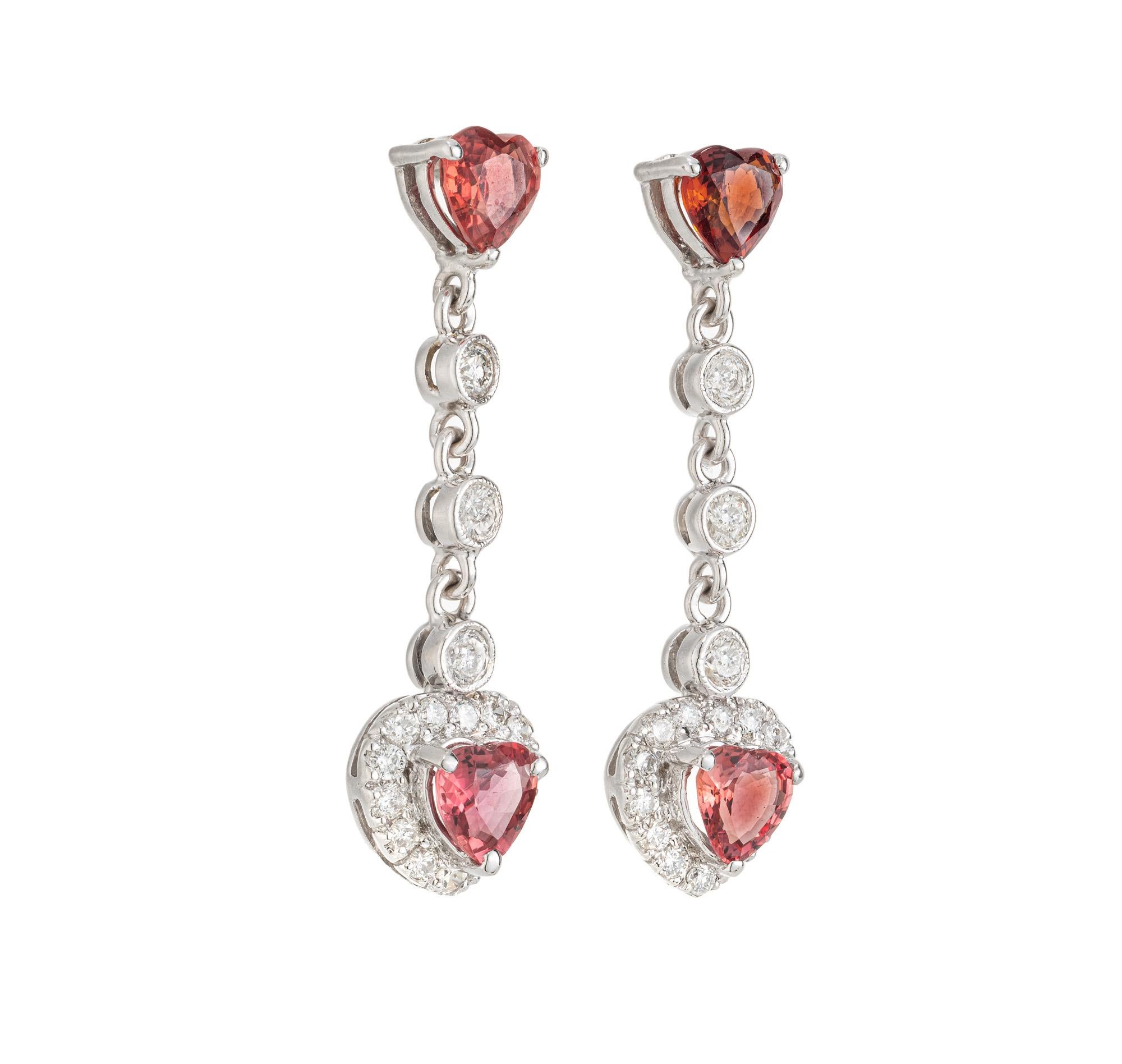 Unique Orange Heart Sapphire Diamond Gold Drop Dangle Earrings. The centerpiece of these earrings are the 4 stunning 1.50 carat orange heart sapphires. The larger dangle sapphires each are framed by a shimmering halo of round cut diamonds. The
