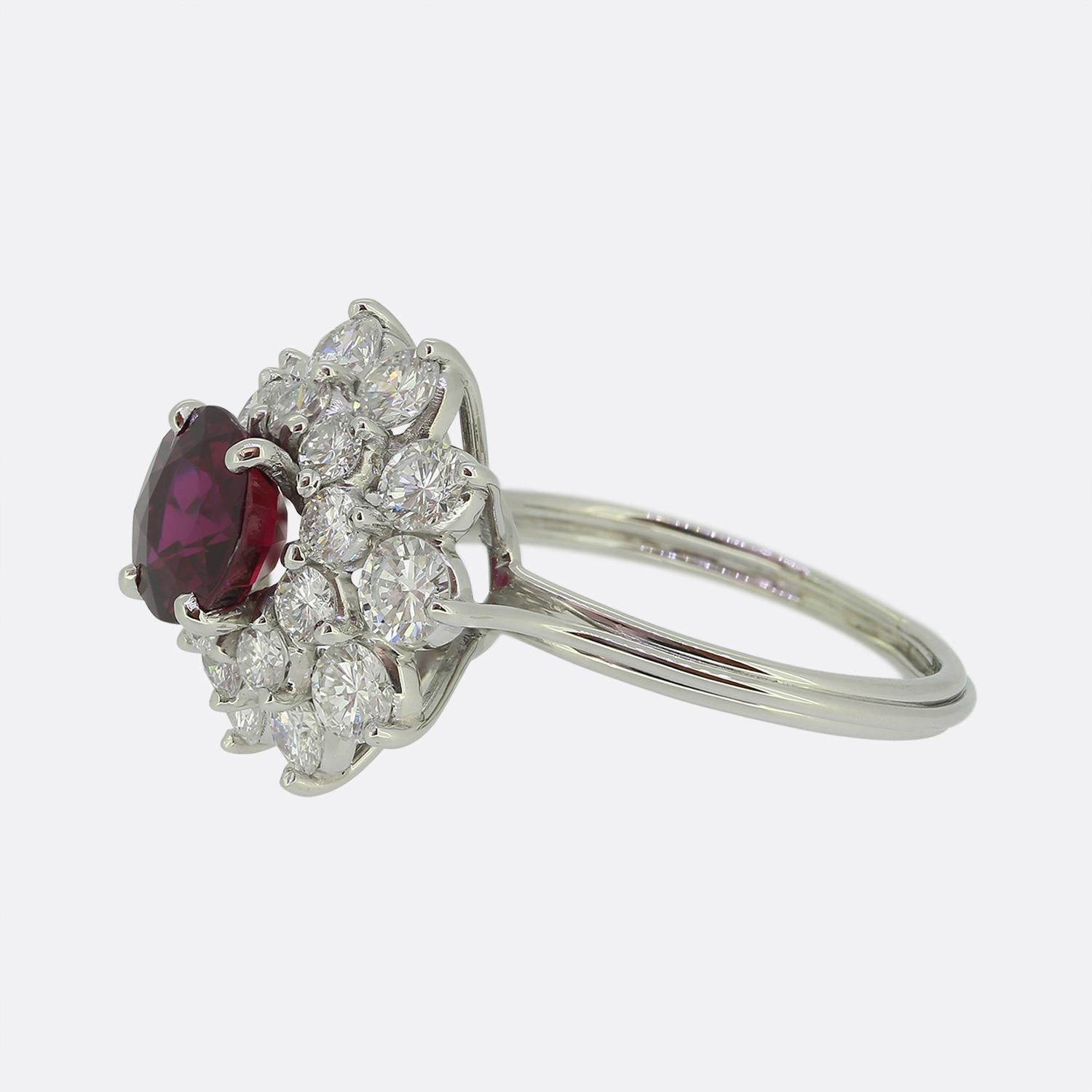 Hier haben wir einen atemberaubenden Rubin- und Diamant-Cluster-Ring. In der Mitte des Gesichts befindet sich ein runder, facettierter, samtig-roter Rubin. Der Hauptstein sitzt stolz in einer Vierkrallenfassung und wird von einer doppelten Umrahmung