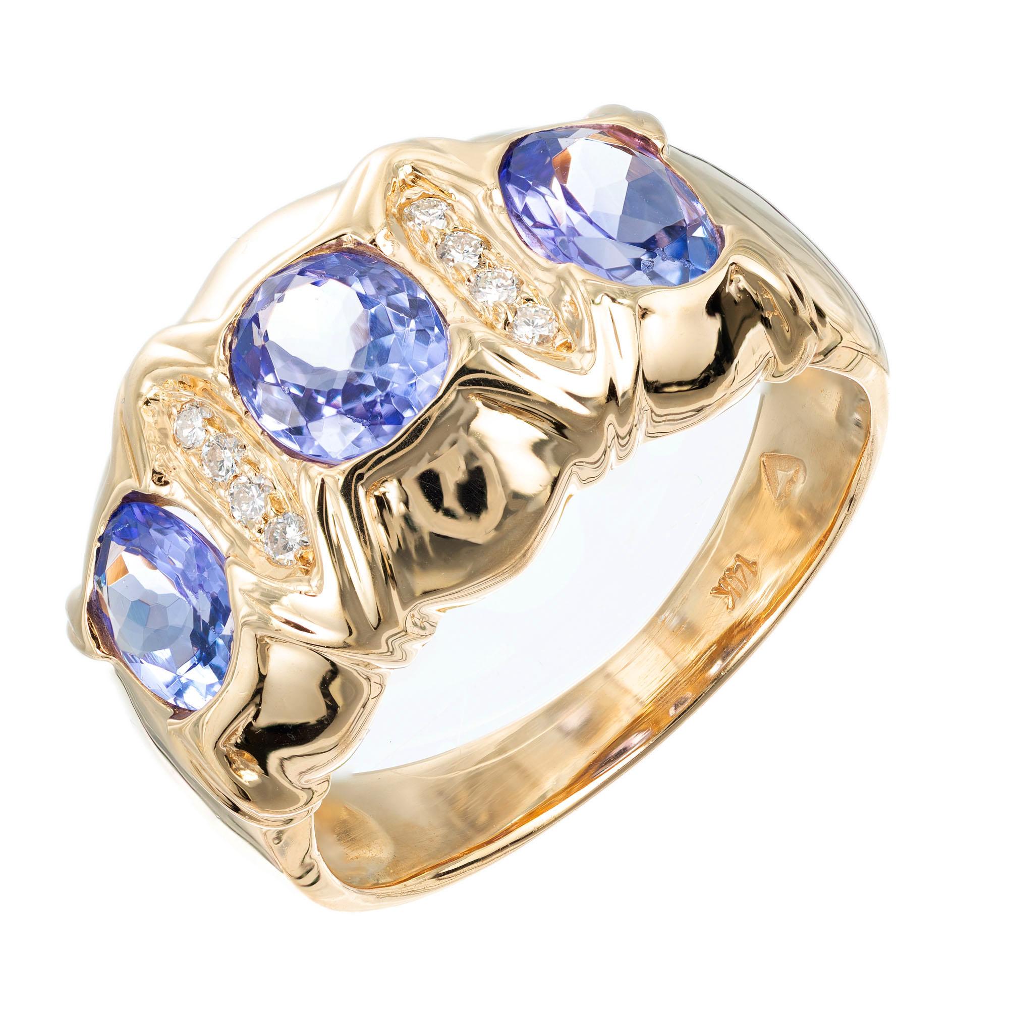 Tansanit und Diamant 12mm breit verjüngt Band Ring. 3 ovale Tansanit-Steine mit 8 runden Akzent-Diamanten in einer Fassung aus 14 Karat Gelbgold. 

3 ovale violettblaue Tansanite, ca. 1,50cts
8 runde Diamanten, G-H SI ca. .10cts
Größe 7,75 und