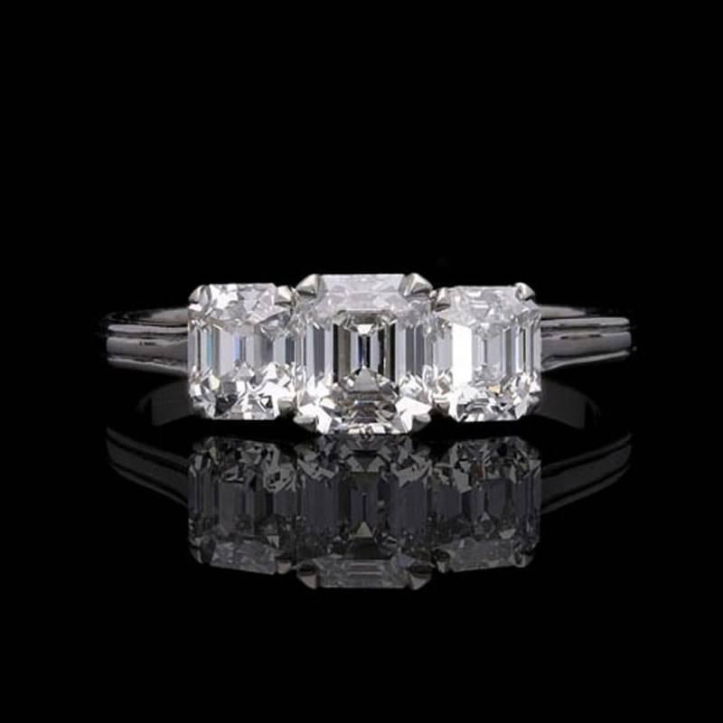 A classically beautiful three stone ring by Hancocks, the central emerald-cut diamond weighing 0.67 carats and of E colour and VS2 clarity corner claw-set between two further emerald-cut diamonds weighing 0.41 carat  and 0.42 carat and both of D
