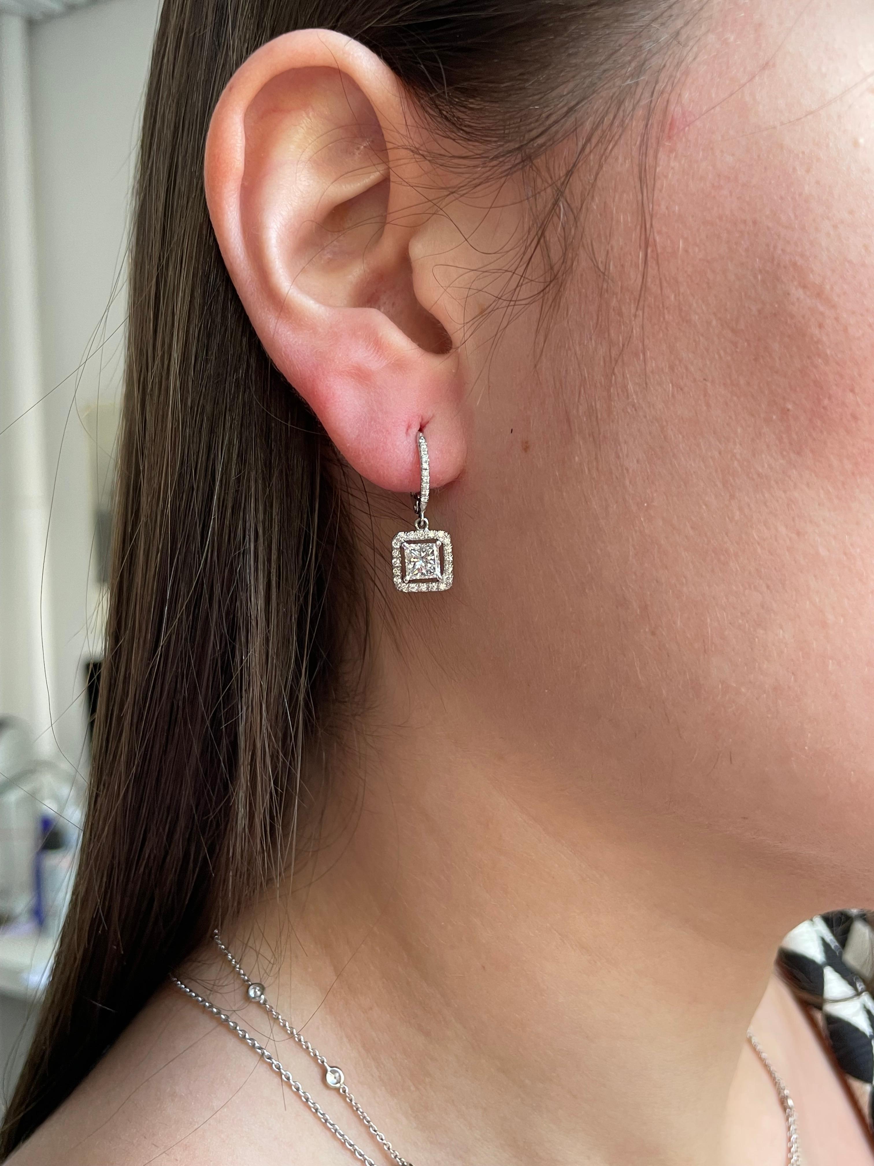 Stunning princess cut dangling earrings. Weighing approximately 1.50 carats these H color and SI clarity diamond earrings have a lever back and will fit any occasion. Each earring has a pave diamond frame and a wire set in 18kt gold. These earrings