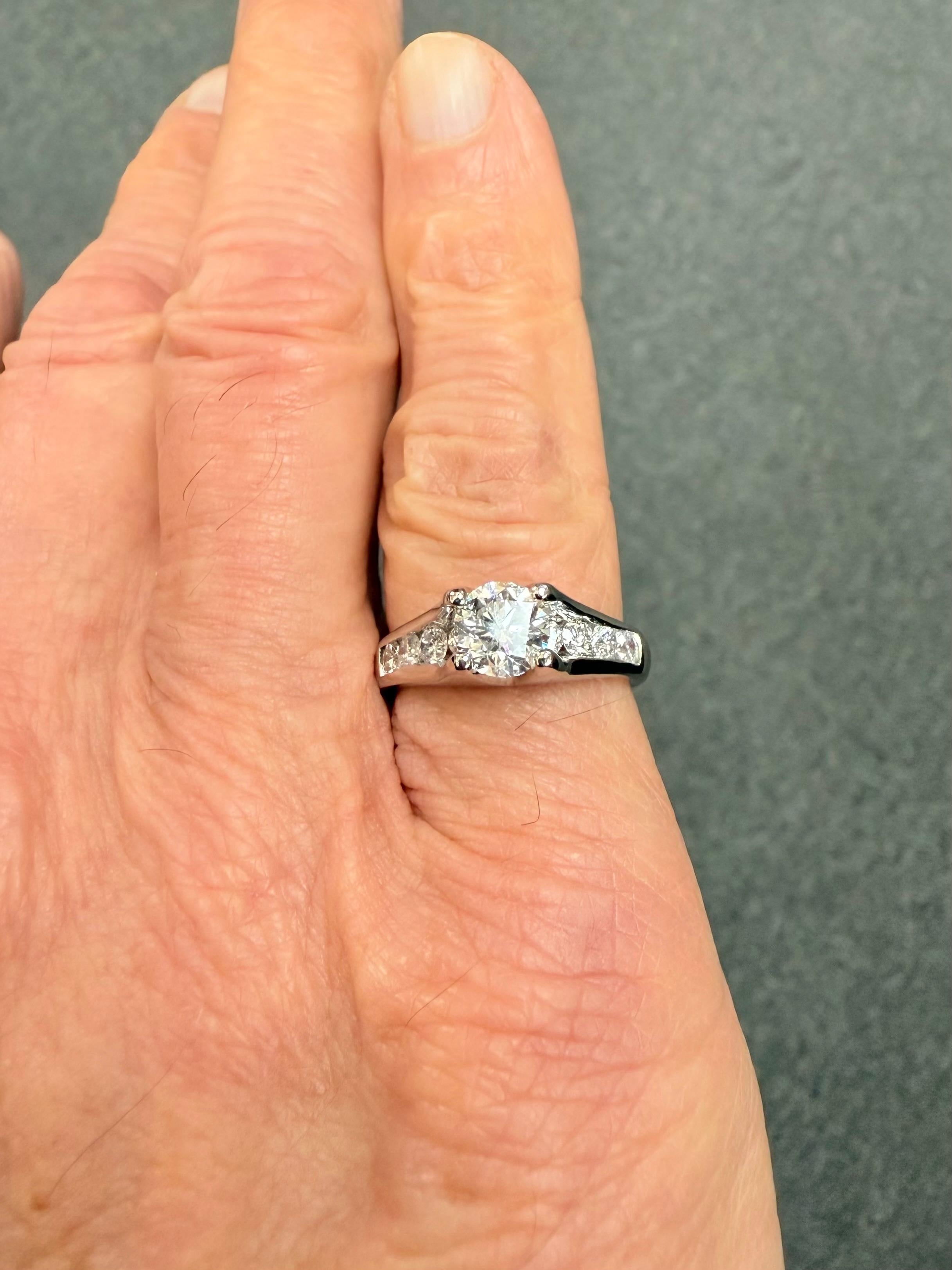 Anillo de compromiso de diamantes en platino de 1,50 quilates TW.

Este precioso anillo de compromiso está engastado con un diamante central redondo de talla brillante que pesa  1,03 quilates junto con 9 diamantes más pequeños que suman