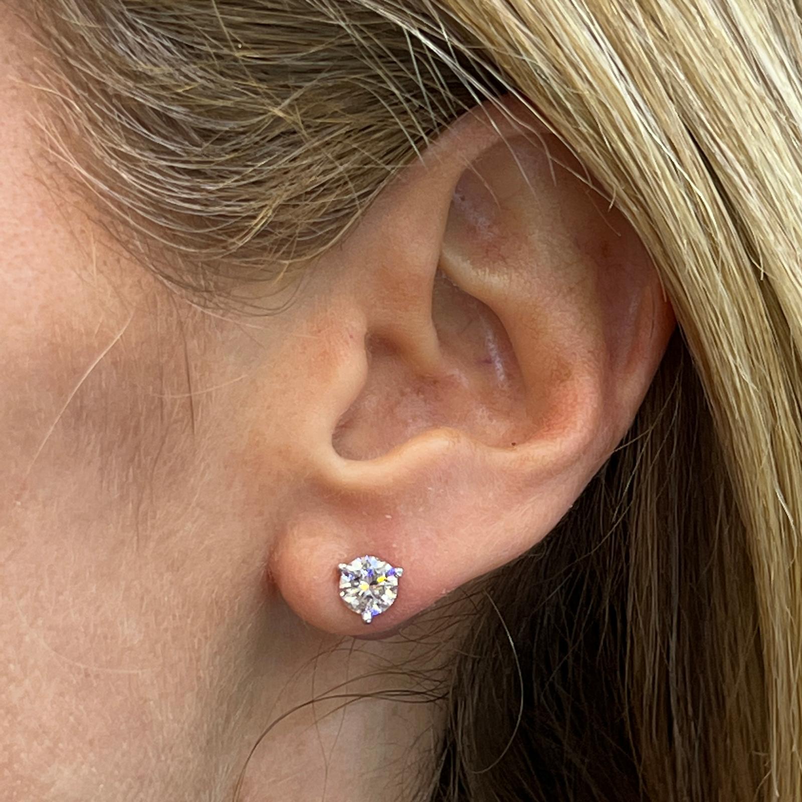Brilliant diamond stud earrings set in 14 karat white gold martini mountings. The matched diamonds weigh a total of 1.50 carat total weight and are GIA certified F/SI2 and G/VS2. 