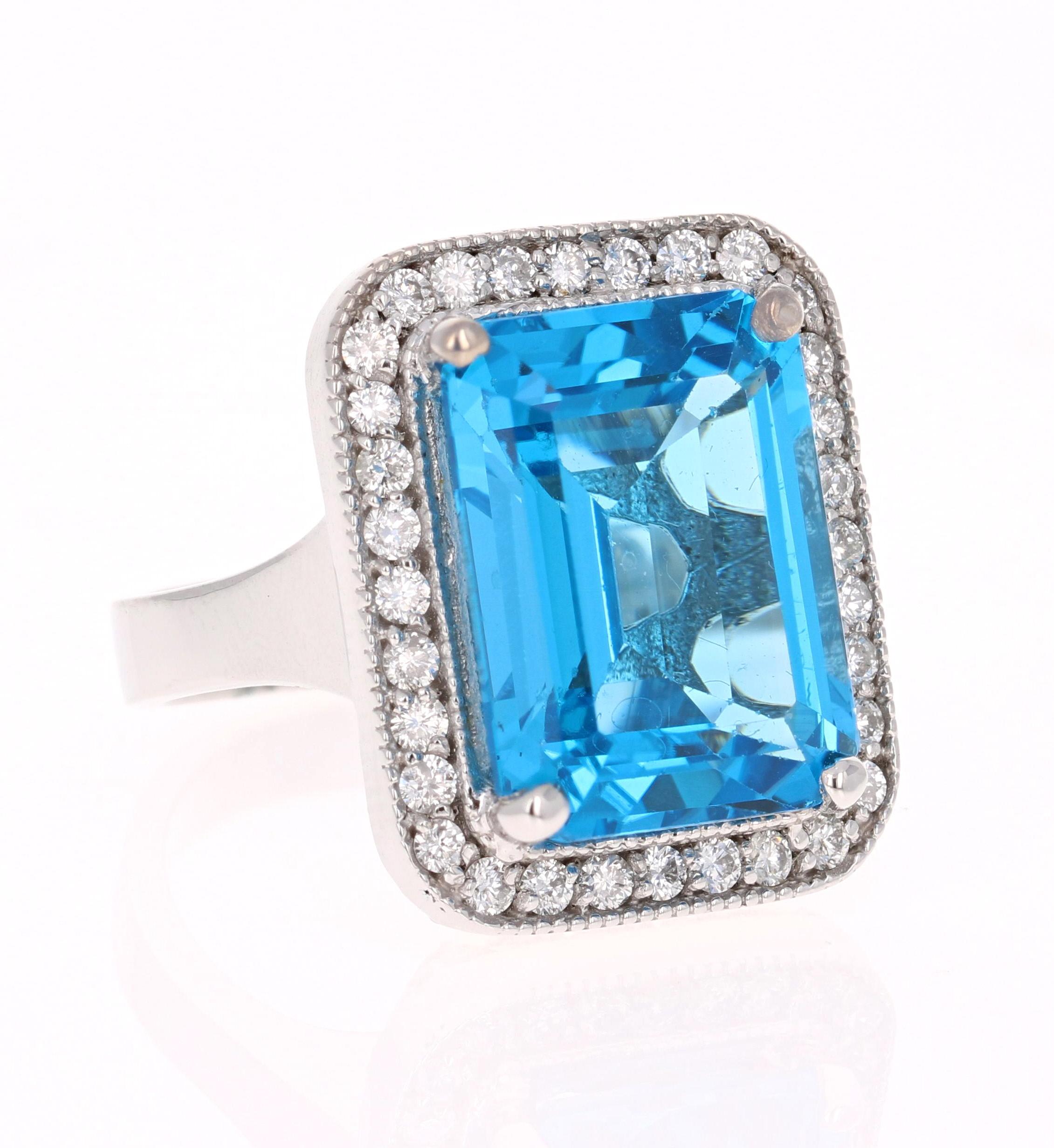 This stunning statement ring has a large Emerald Cut Blue Topaz that weighs 13.94 Carats. 
It is surrounded by a simple halo of 46 Round Cut Diamonds that weigh 1.11 Carats. 
The total carat weight of the ring is 15.05 Carats. 

It is crafted in 14