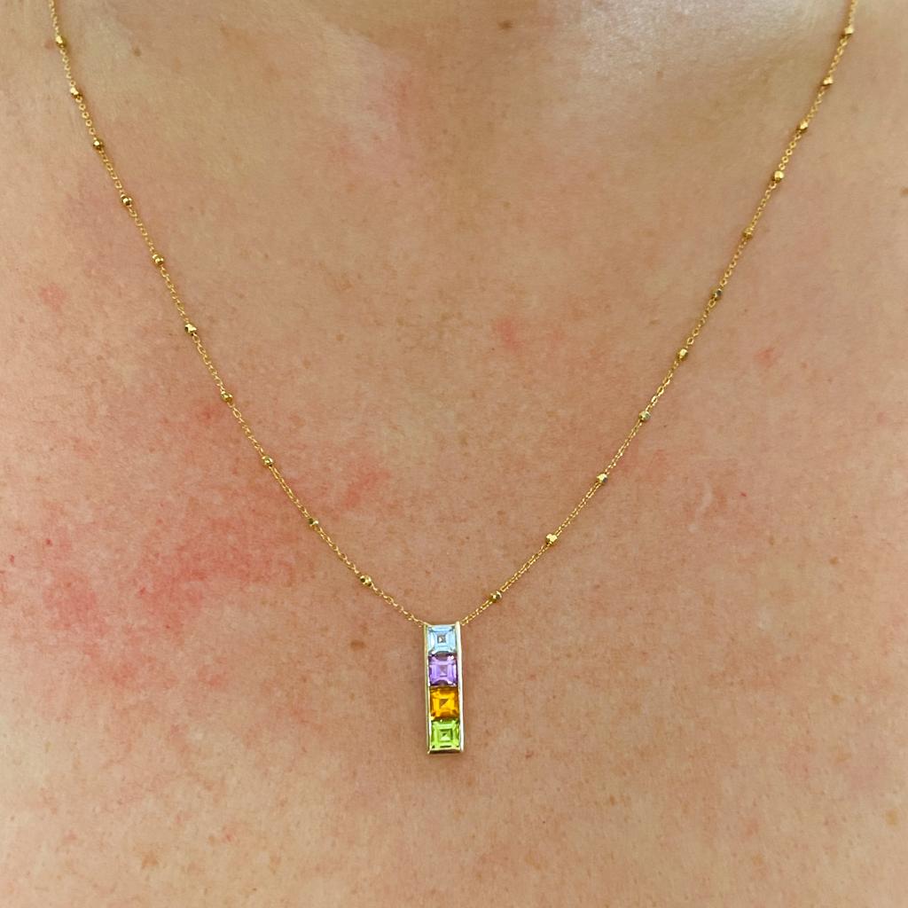 This sleek geometric bar pendant has beautiful colors in a slim-line minimalist look. The rectangular straight lines of this bezel-set beauty will be perfect on you! The square colorful gemstones are blue topaz, amethyst, citrine, and peridot. These