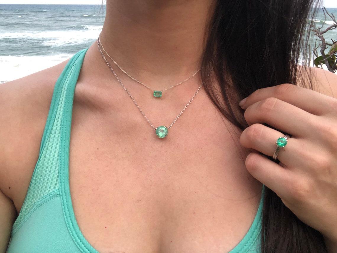 Featured here is a 1.50-carat stunning, emerald necklace in fine sterling silver. Displayed in the center is a medium-light green emerald with very good eye clarity, accented by a simple four-prong silver mount, allowing for the emerald to be shown
