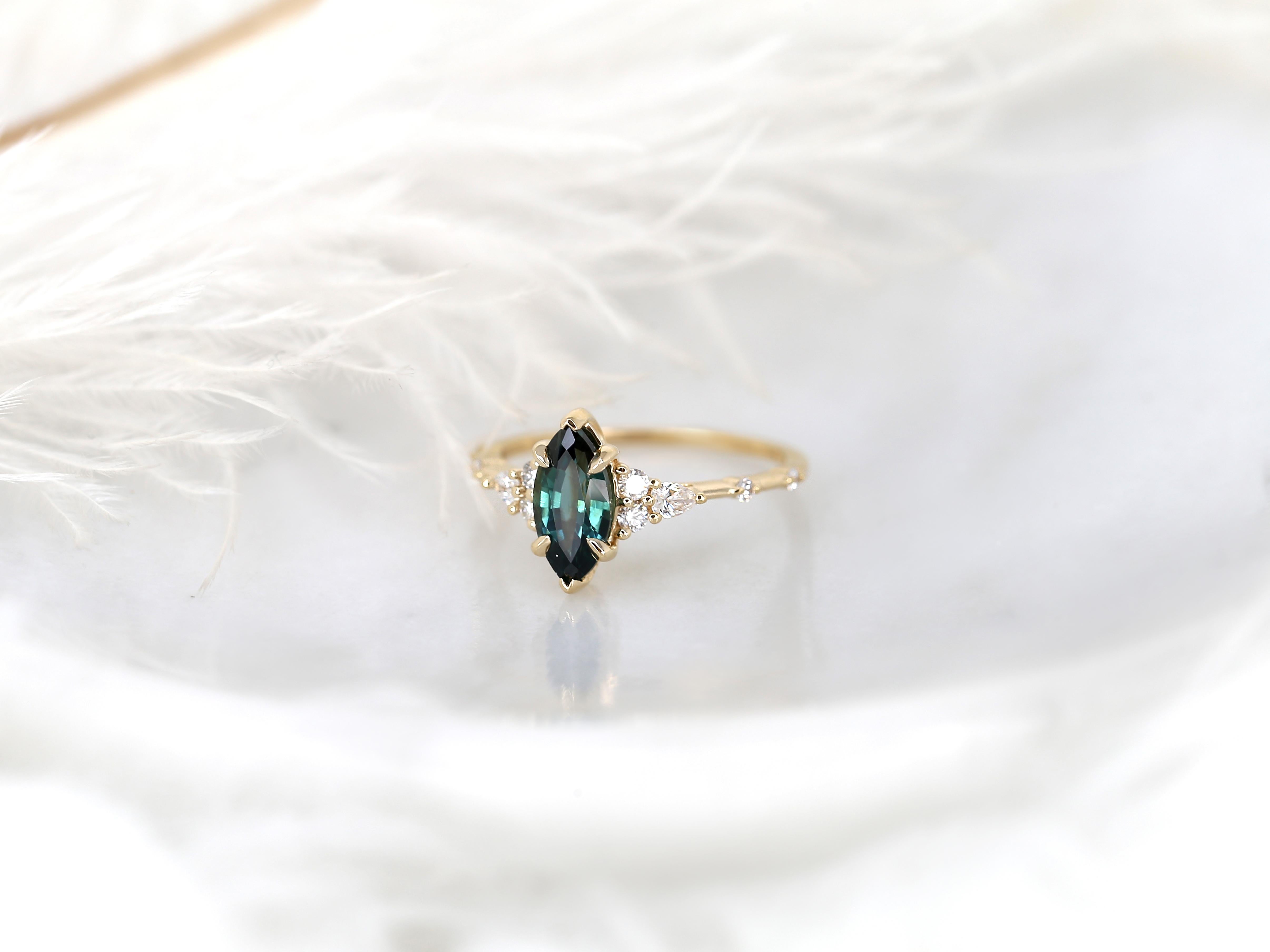 Discover elegance and individuality with our handmade Astrid marquise teal sapphire cluster ring. Crafted in 14kt yellow gold, its dainty shank and distinctive clusters east and west of the center stone captivate with timeless charm.

Details of