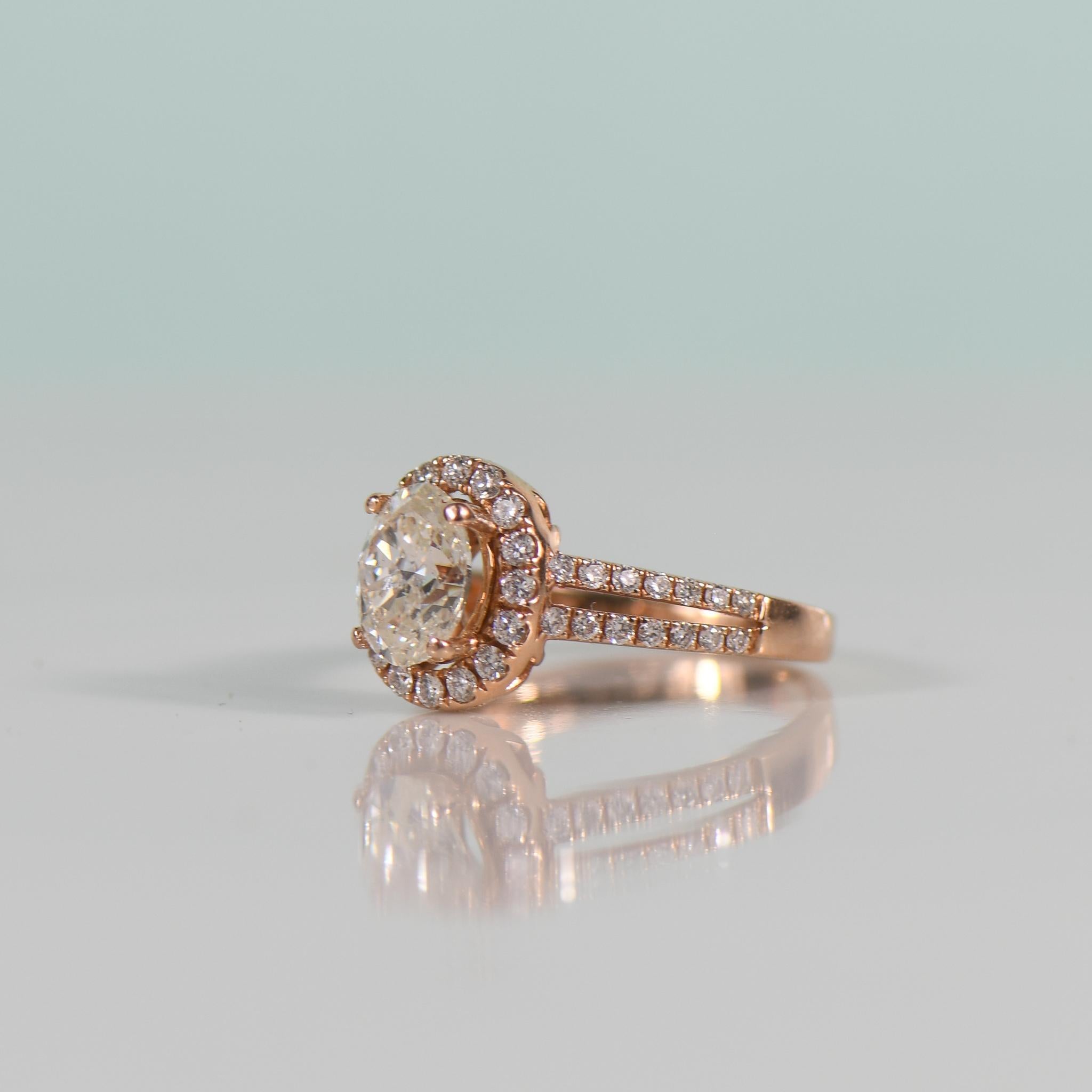 Indulge in the exquisite beauty of this enchanting ring, featuring a dazzling 1.50 carat oval GIA-certified natural diamond embraced by a halo of shimmering diamonds, all set in lustrous rose gold. The split shank design adds a touch of contemporary